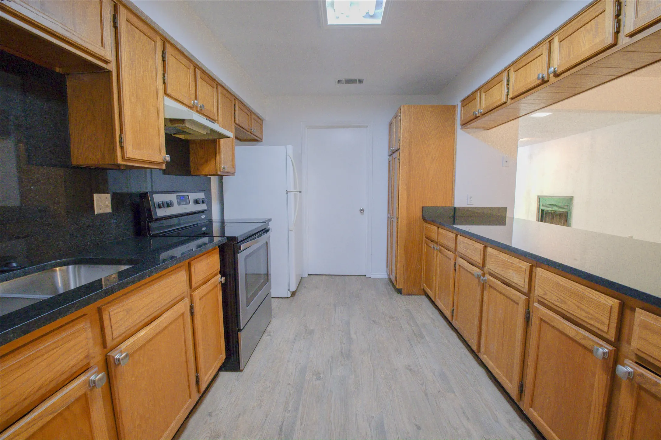 Kitchen featuring wood-finish cabinetry, dark countertops, and stainless steel appliances