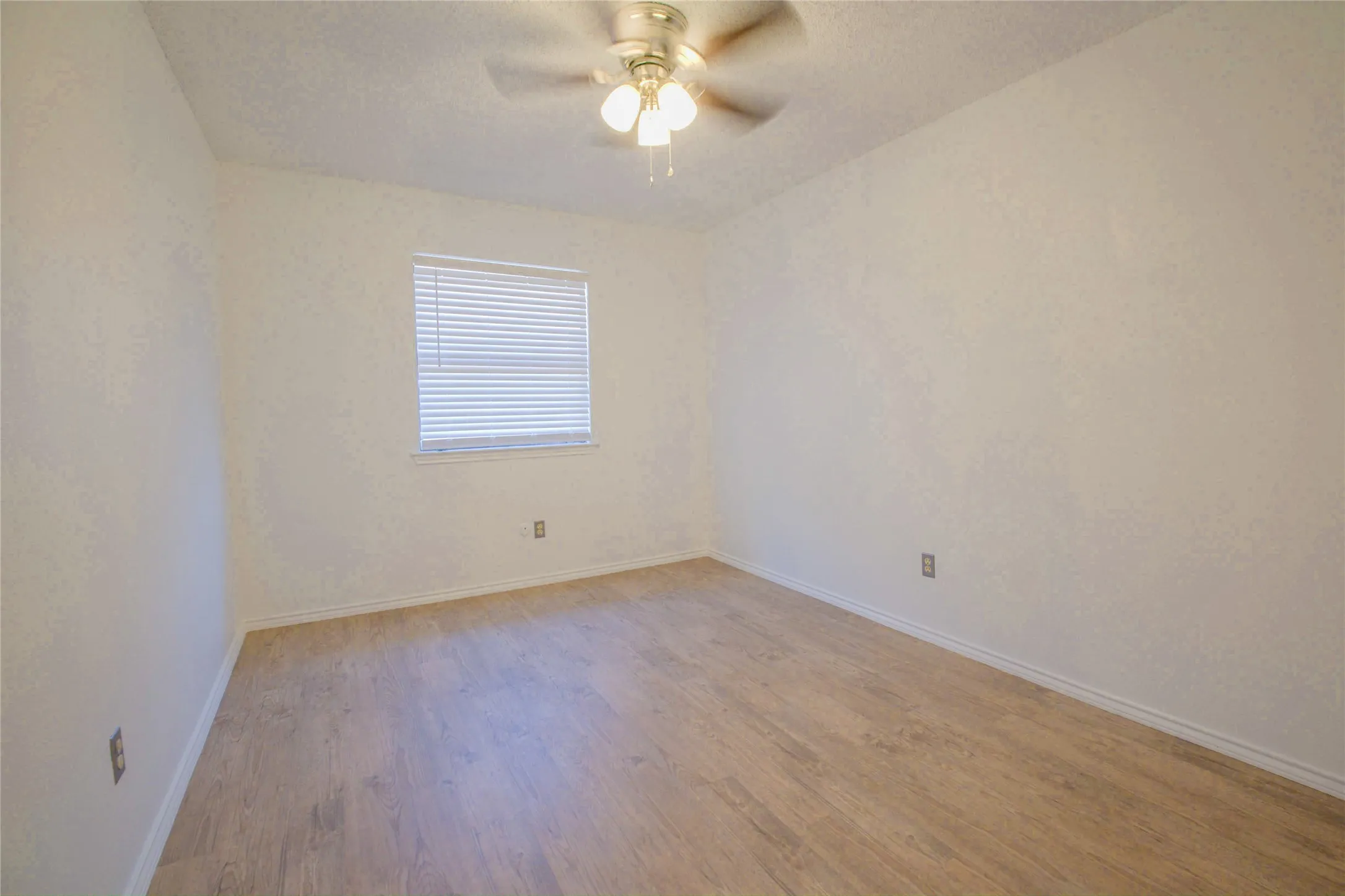 Wood-finish flooring, ceiling fan with integrated lighting, and a window with horizontal blinds