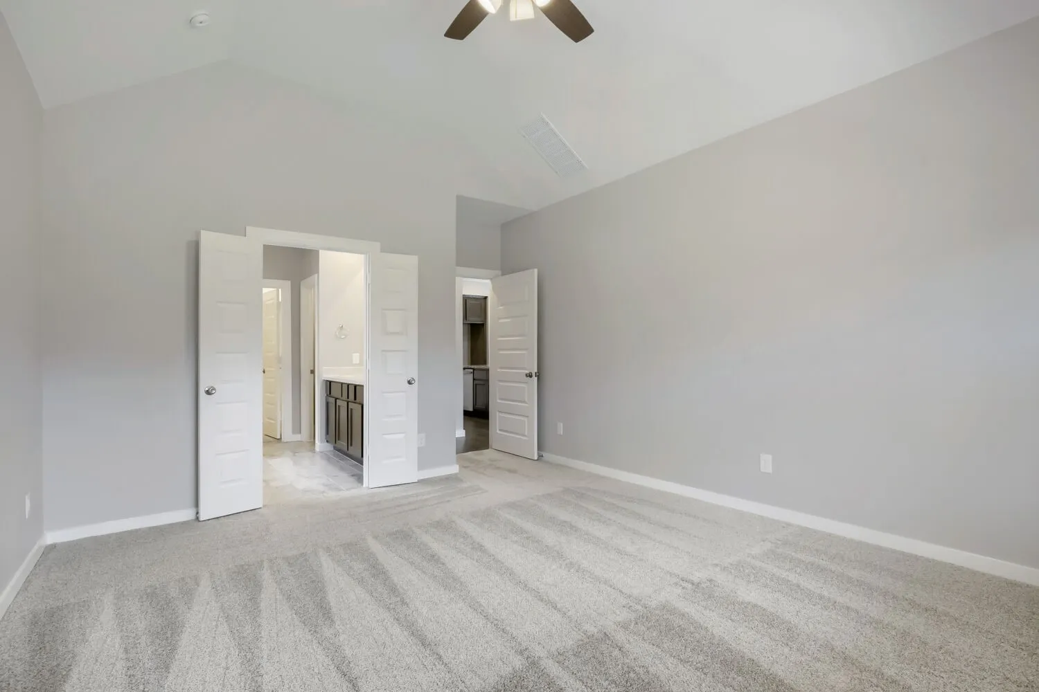 Vaulted ceilings, neutral wall tones, and installed ceiling fan with light fixture