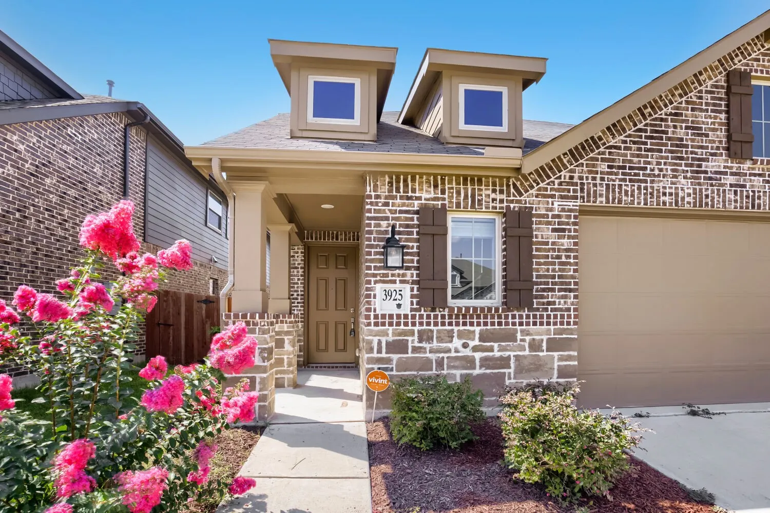 Charming brick facade with distinctive dual dormers and arched entryway