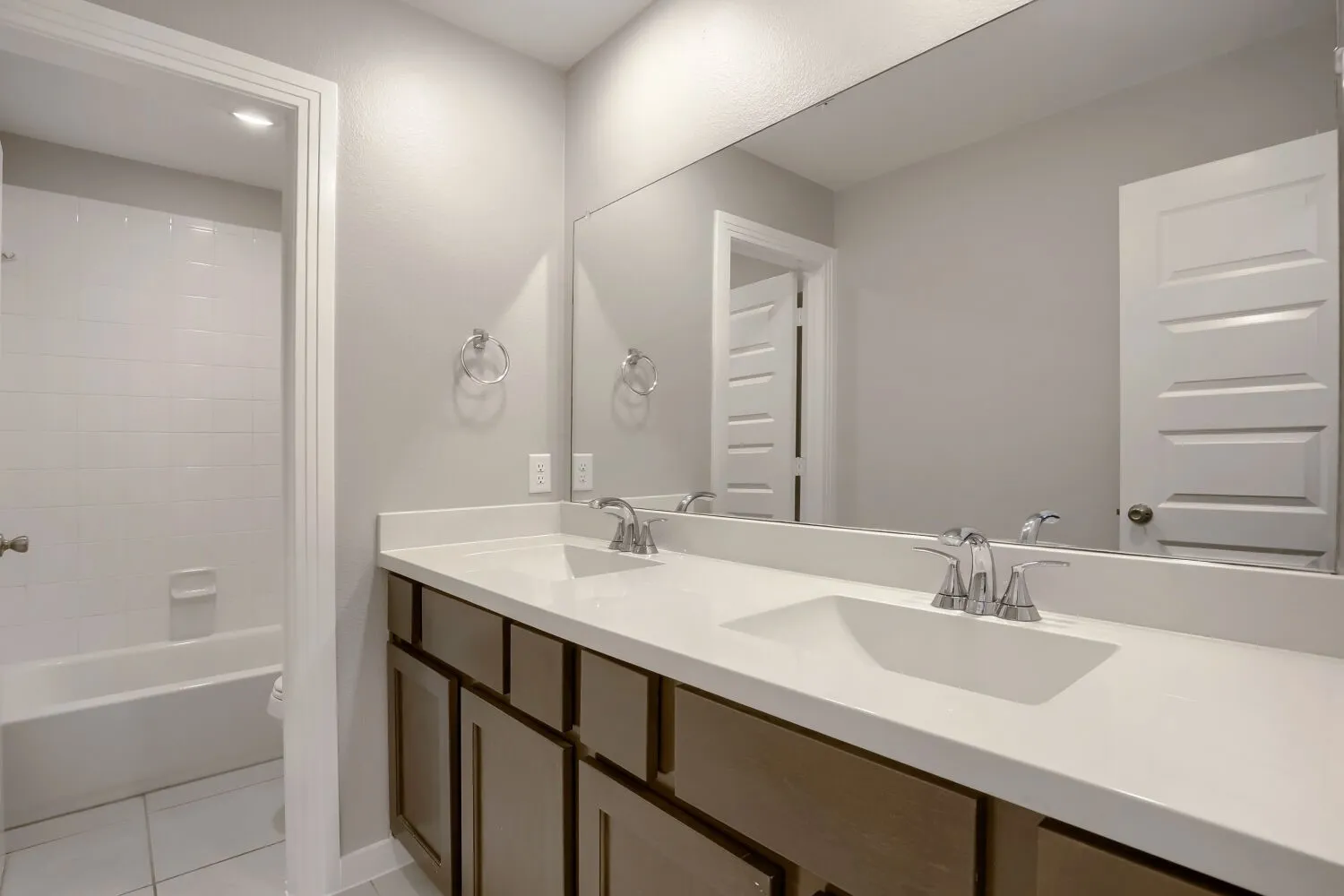 Dual vanity with integrated sinks, chrome fixtures, and a large wall-mounted mirror