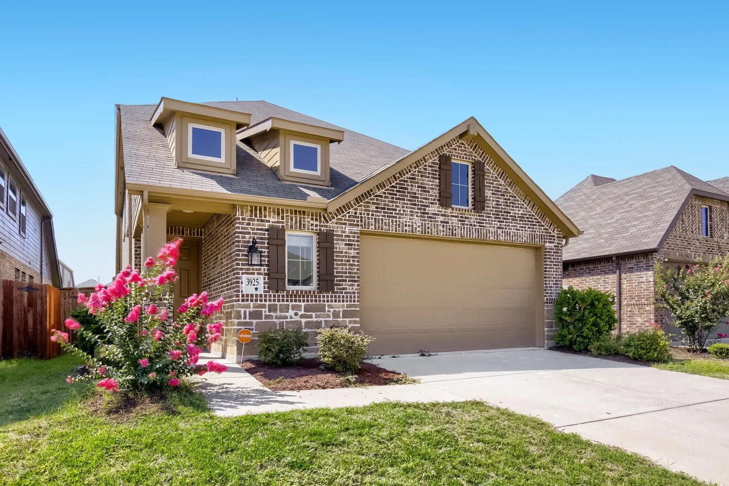 Brick and stone exterior with dormer windows, attached two-car garage, and concrete driveway