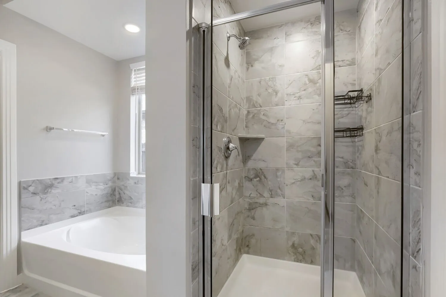Walk-in shower with clear glass enclosure, tiled walls, and built-in shelving