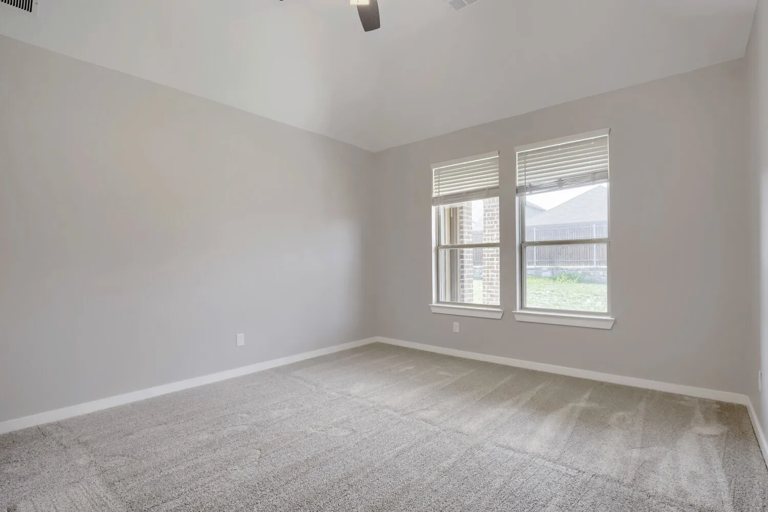 Plush carpeting, neutral wall color, two windows, and a ceiling fan with integrated lighting