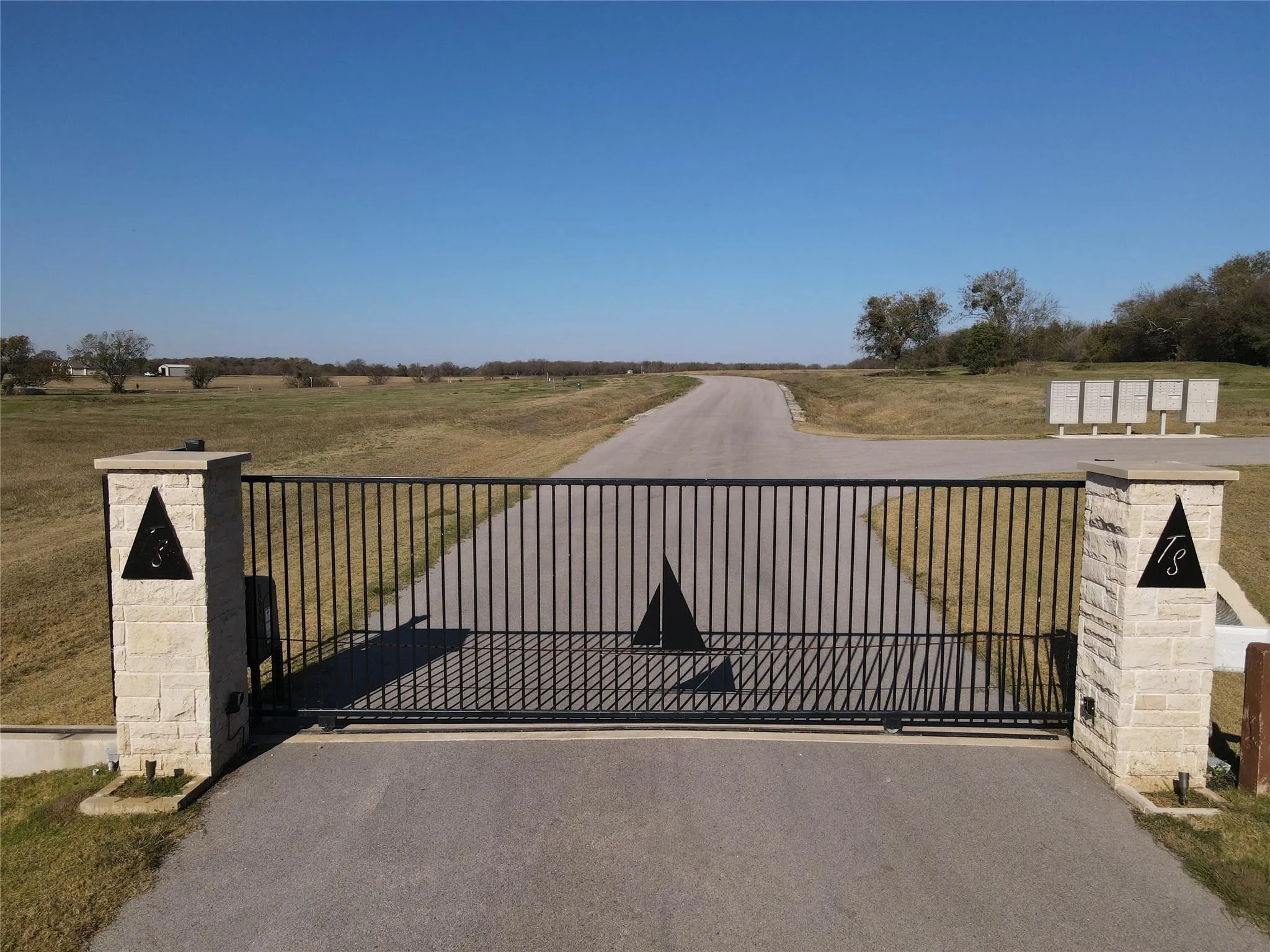 Gated entry with stone columns and a black metal gate