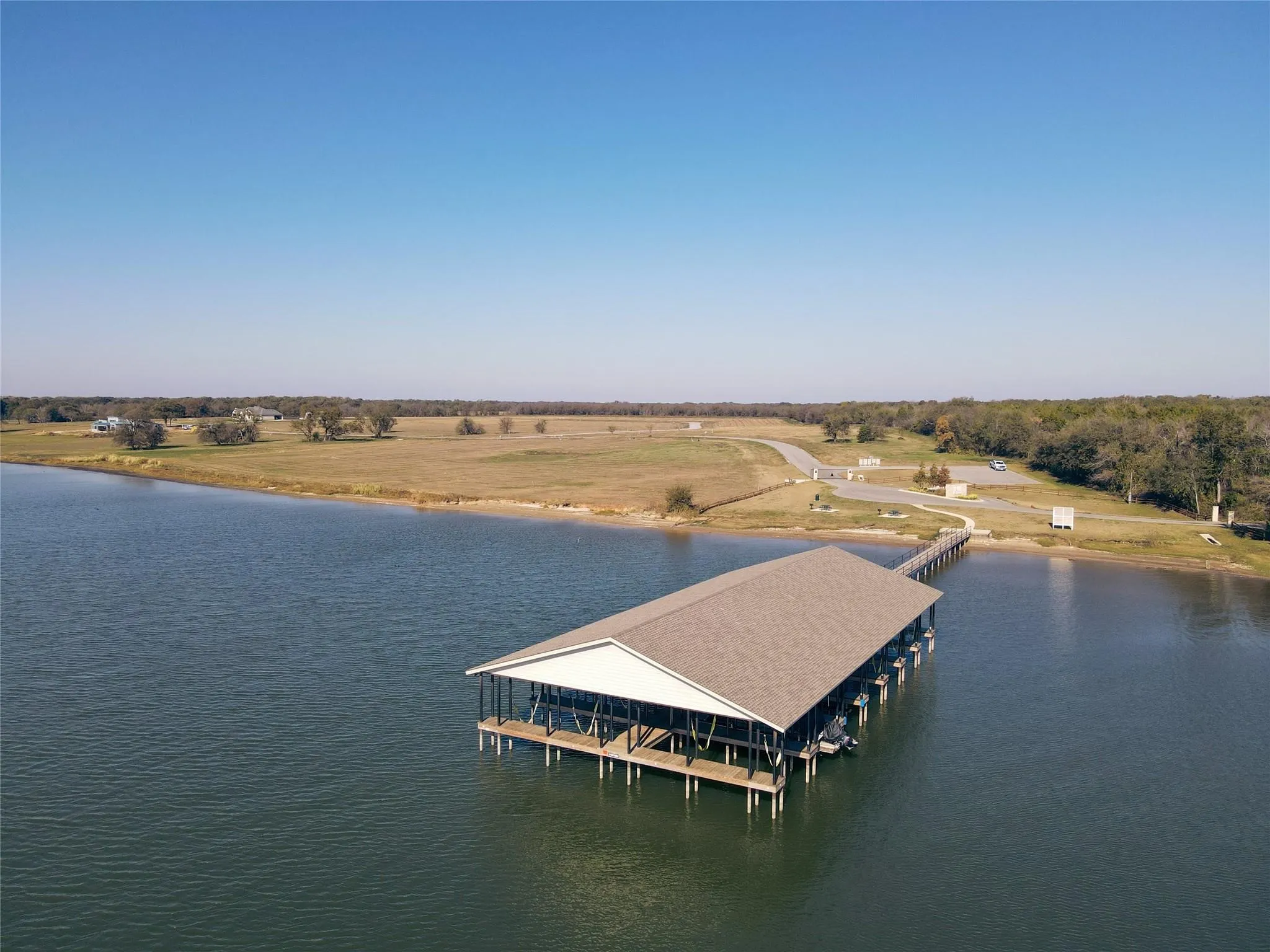 Expansive waterfront featuring a multi-slip covered boat dock, extended pier, and natural shoreline