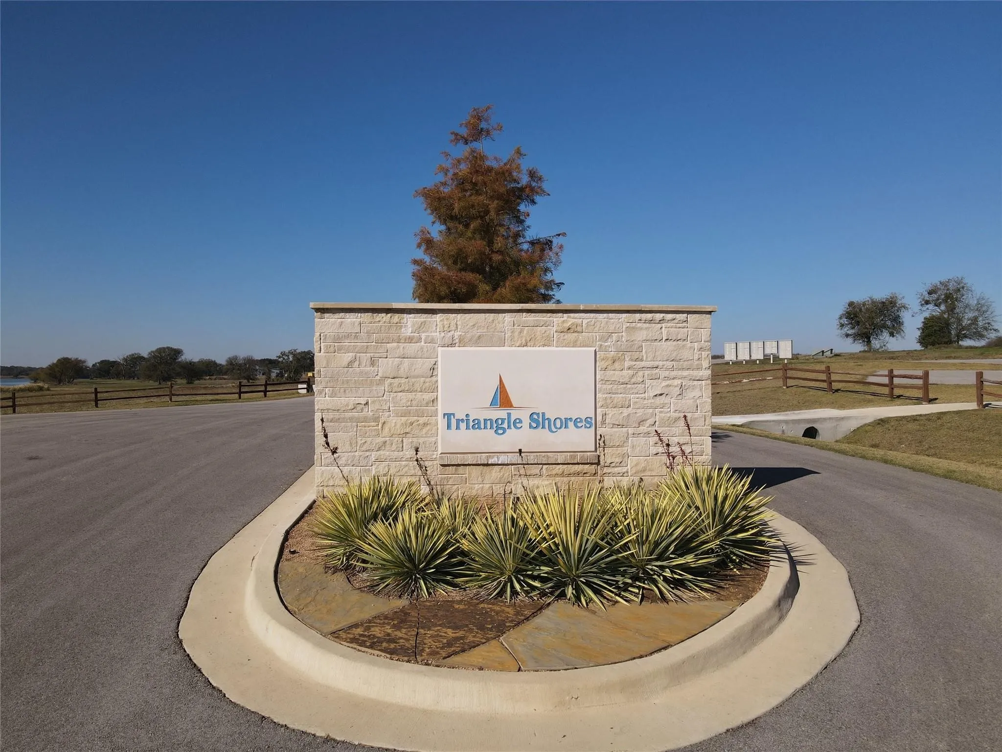 Stone-clad monument sign with integrated signage, surrounded by mature landscaping and a paved entrance