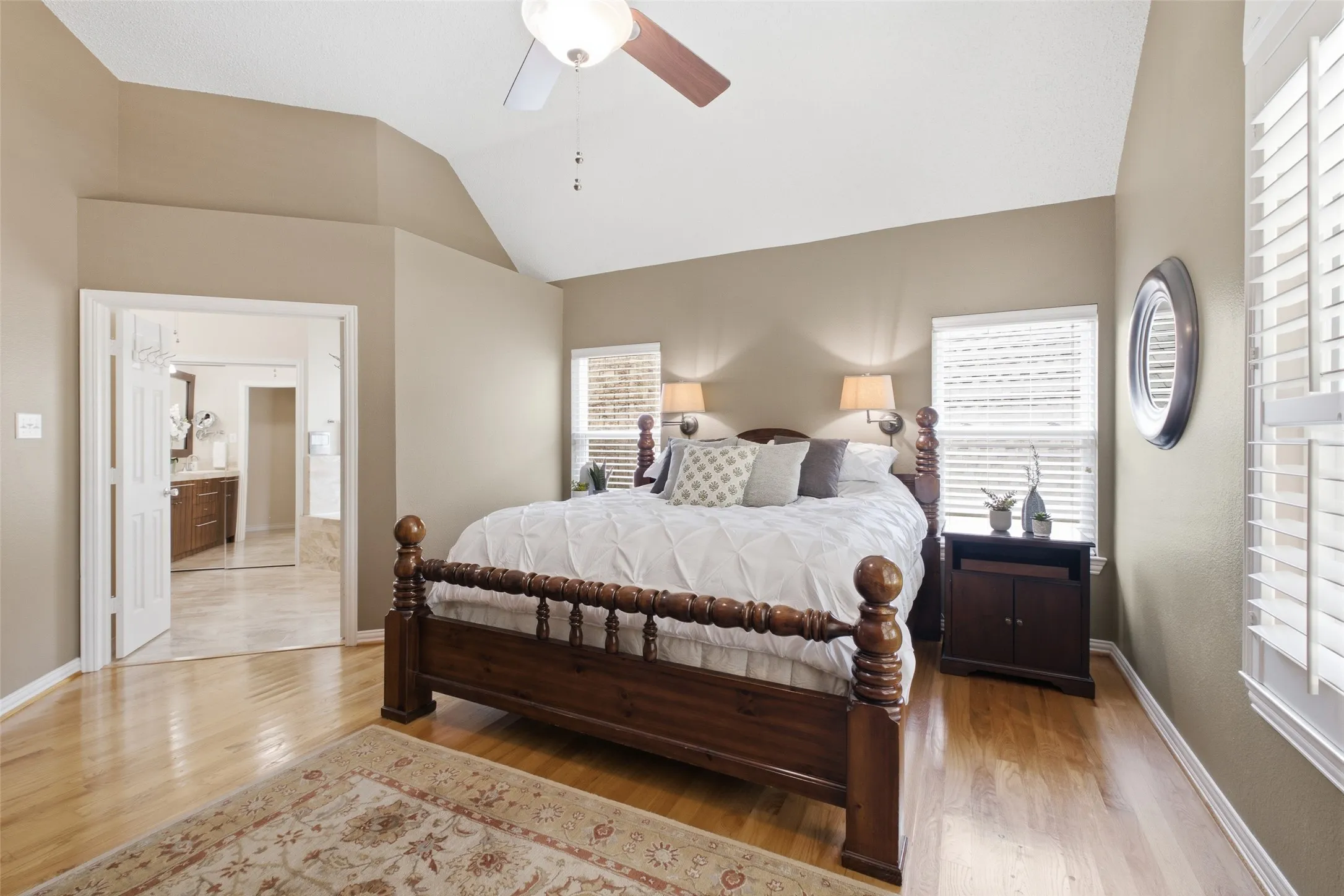 Spacious primary bedroom with vaulted ceilings, plantation shutters, a four-poster bed, and direct access to the spa-quality en-suite bathroom.