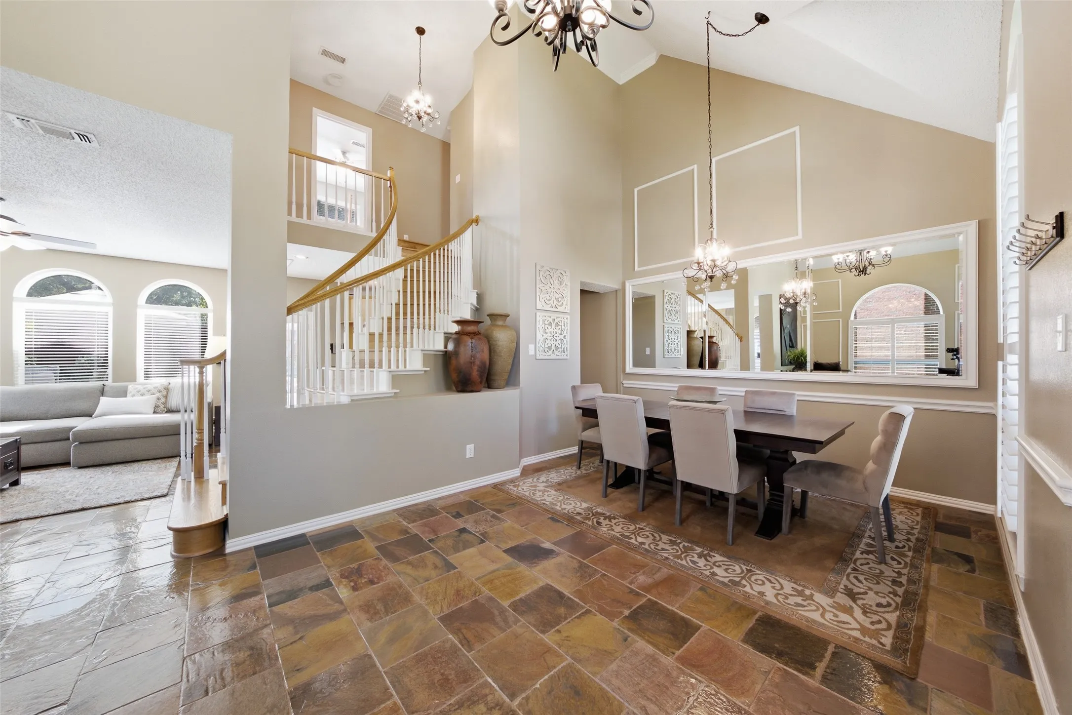 Formal dining room with dramatic vaulted ceilings, decorative mirror, and seamless connection to both the formal living room and family areas of the home.