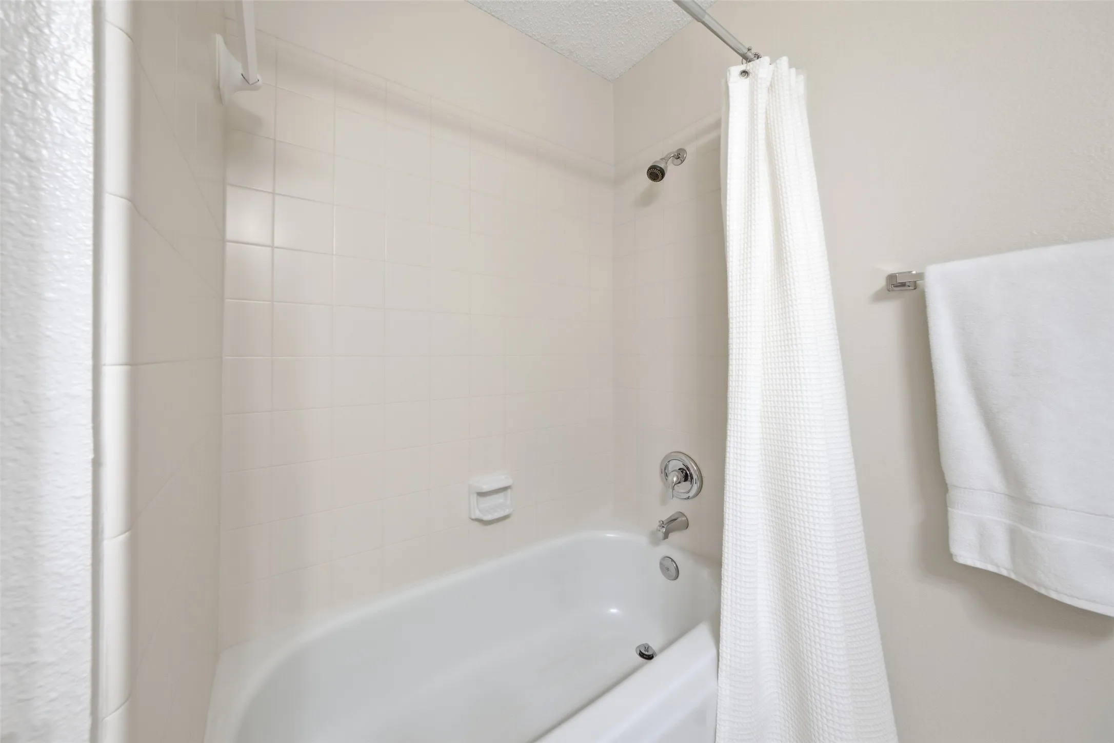 Full secondary bathroom with a tub/shower combination and clean tile surround — functional and well-maintained.
