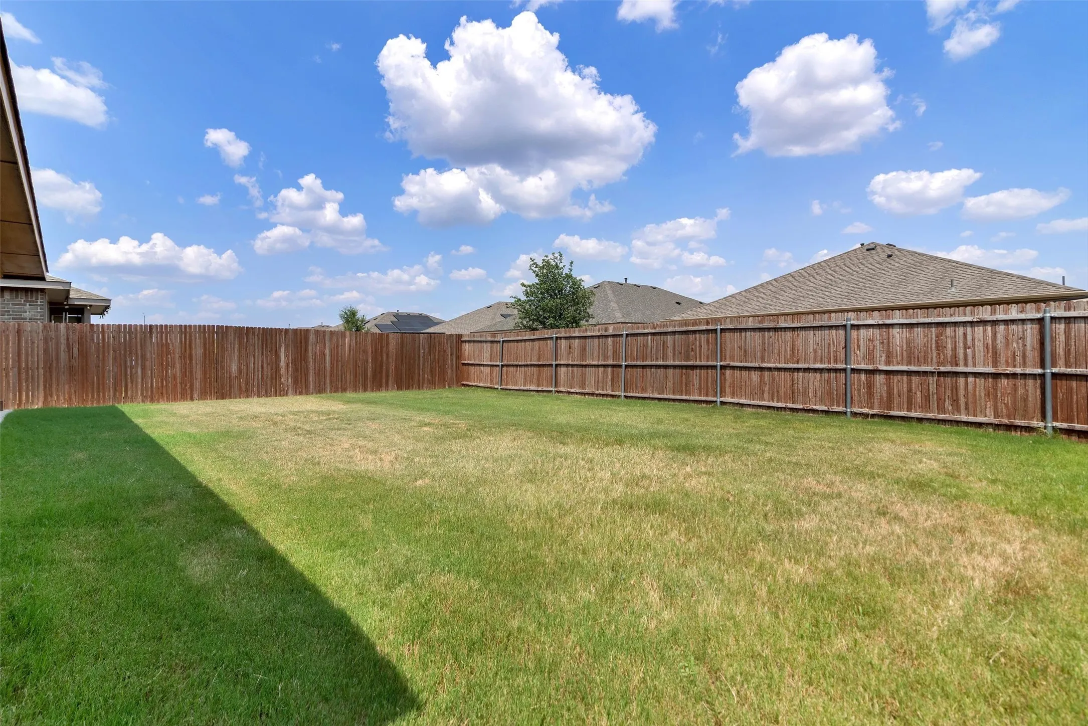 Expansive grassy yard with full privacy fencing