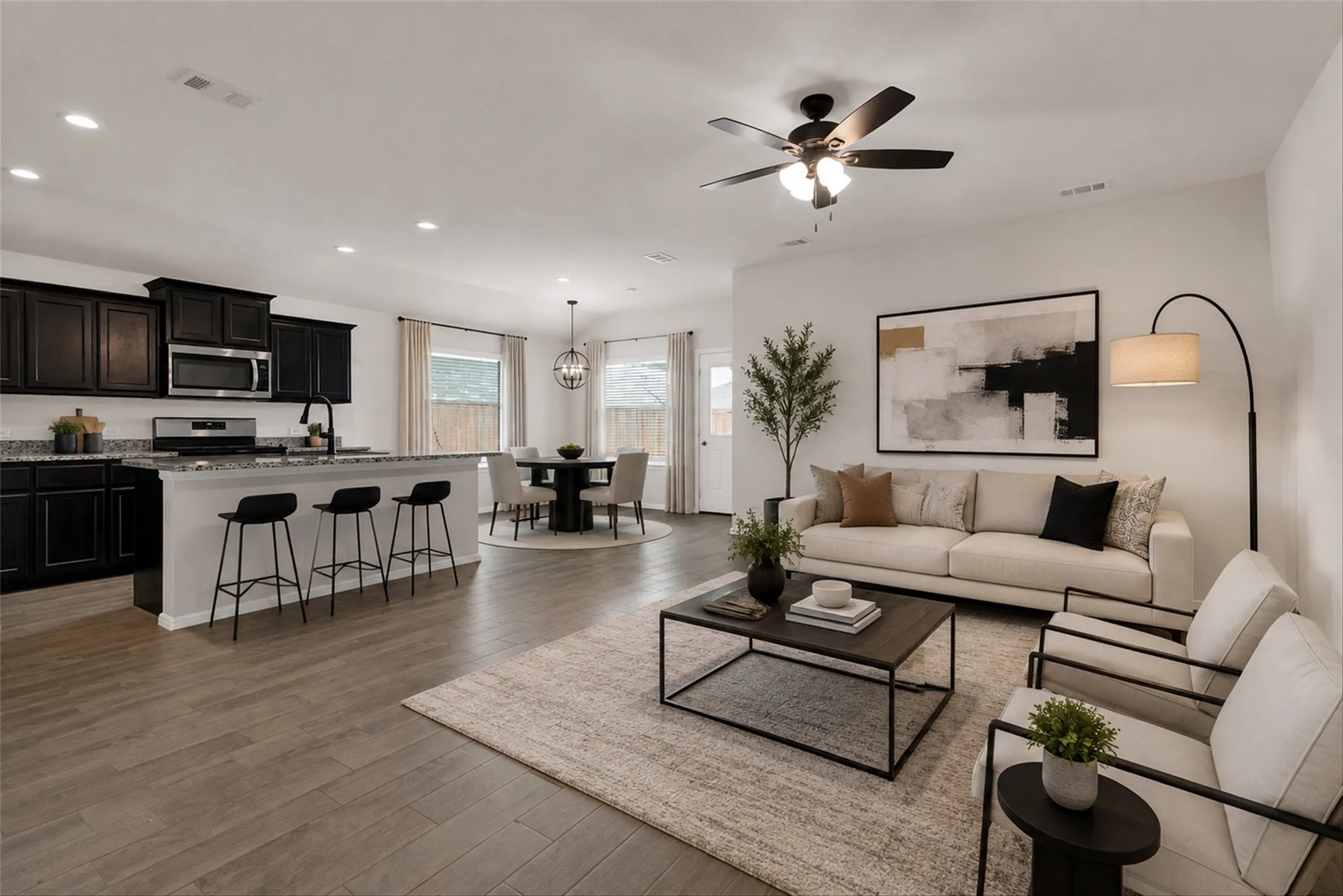 Open-concept living space featuring wood-finish flooring, a kitchen island with seating, dark wood cabinetry, and recessed lighting