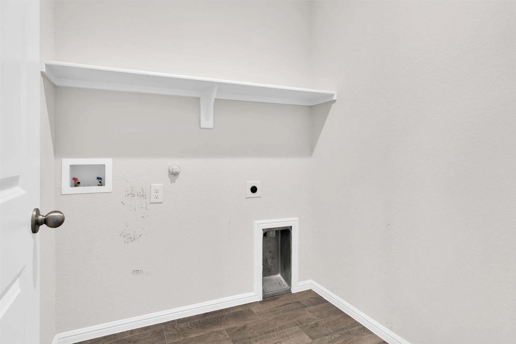 Utility area featuring a wall-mounted shelf, dedicated appliance hookups, and wood-finish flooring