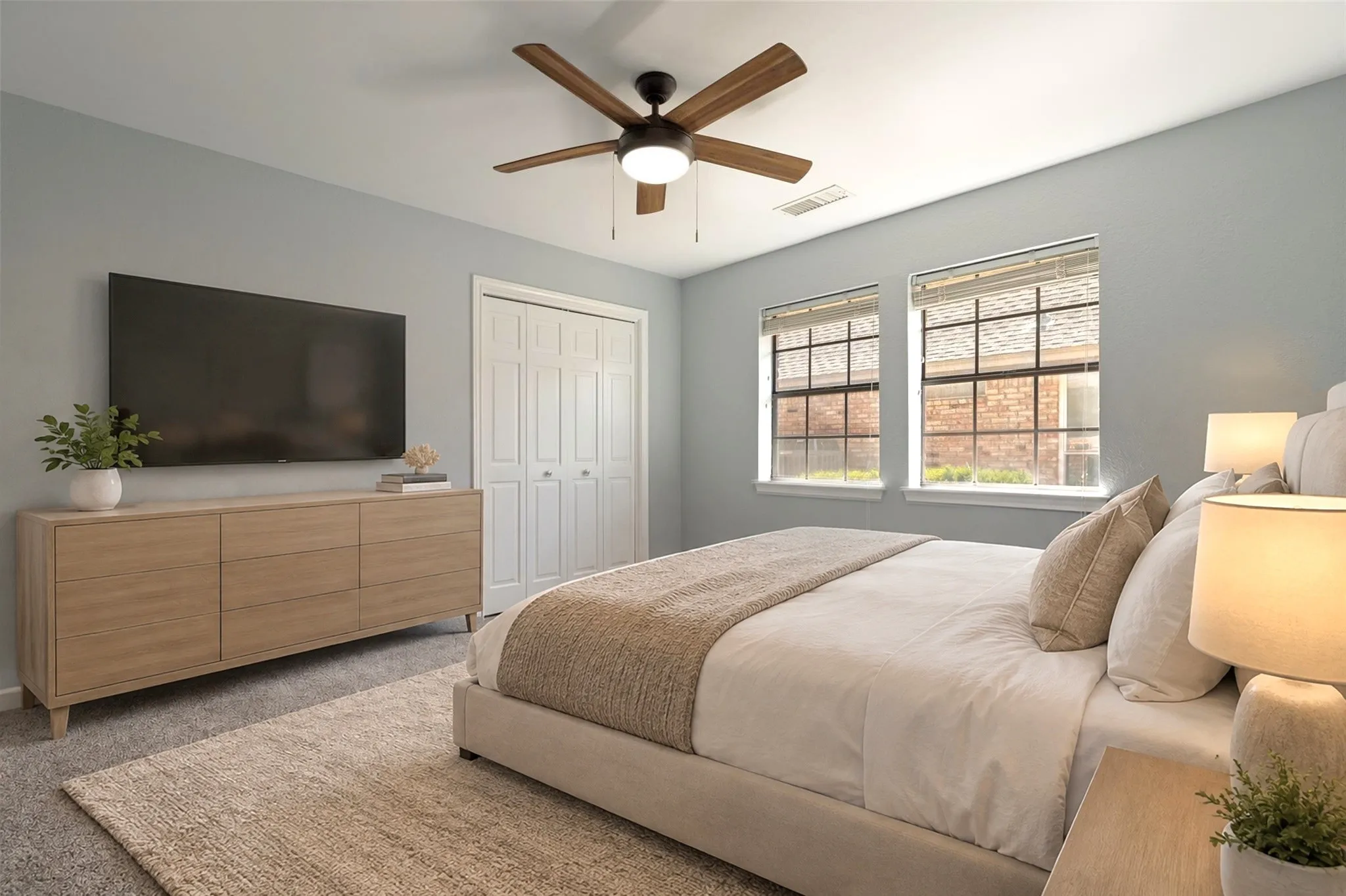 This bedroom located on the first floor feels bright and welcoming thanks to its double windowas that bring in soft natural light. The neutral walls and light gray carpeting create a calm, modern backdrop that suits any décor style. A ceiling fan with wooden blades adds comfort and a touch of sophistication, while the double-door closet provides practical storage. Clean, fresh, and move-in ready, this bedroom is a versatile space within the home’s thoughtful four-bedroom layout.