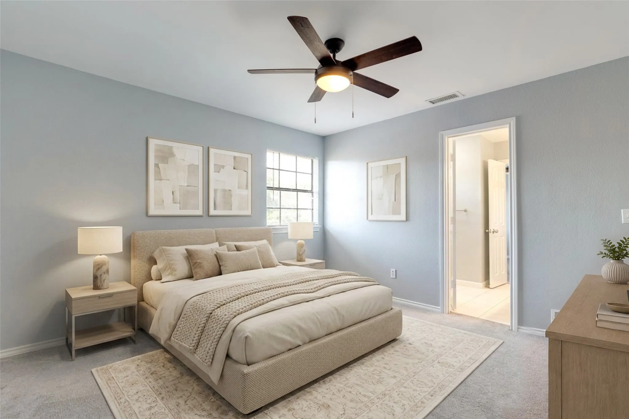 This bedroom offers a fresh, modern feel with its soft neutral walls and light gray carpeting, creating a calm and versatile space. A window with white trim brings in natural light, while the ceiling fan with dark blades adds both comfort and style. The open doorway leads directly into the adjoining bathroom, highlighting the home’s thoughtful layout and easy flow. As one of the additional bedrooms, this room is move-in ready and adaptable for a variety of uses.