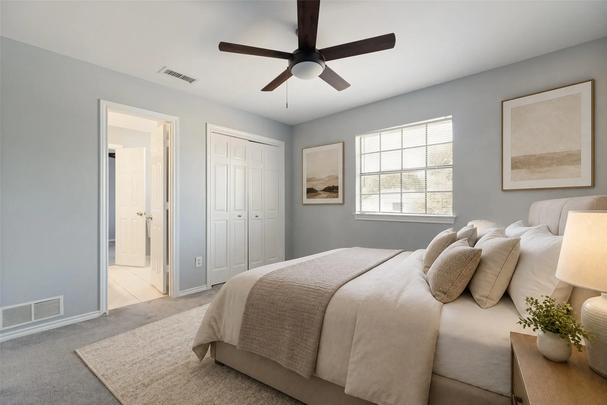 This bright secondary bedroom offers a clean, modern feel with its soft neutral walls and fresh gray carpeting. A window with blinds brings in natural light, creating a comfortable and inviting atmosphere. The double closet doors provide excellent storage, while the ceiling fan with dark blades adds both style and everyday practicality. An open doorway leads into the adjacent tiled area, highlighting the home’s thoughtful layout. As one of the four bedrooms, this space is versatile and move-in ready, easily adapting to a variety of needs.
