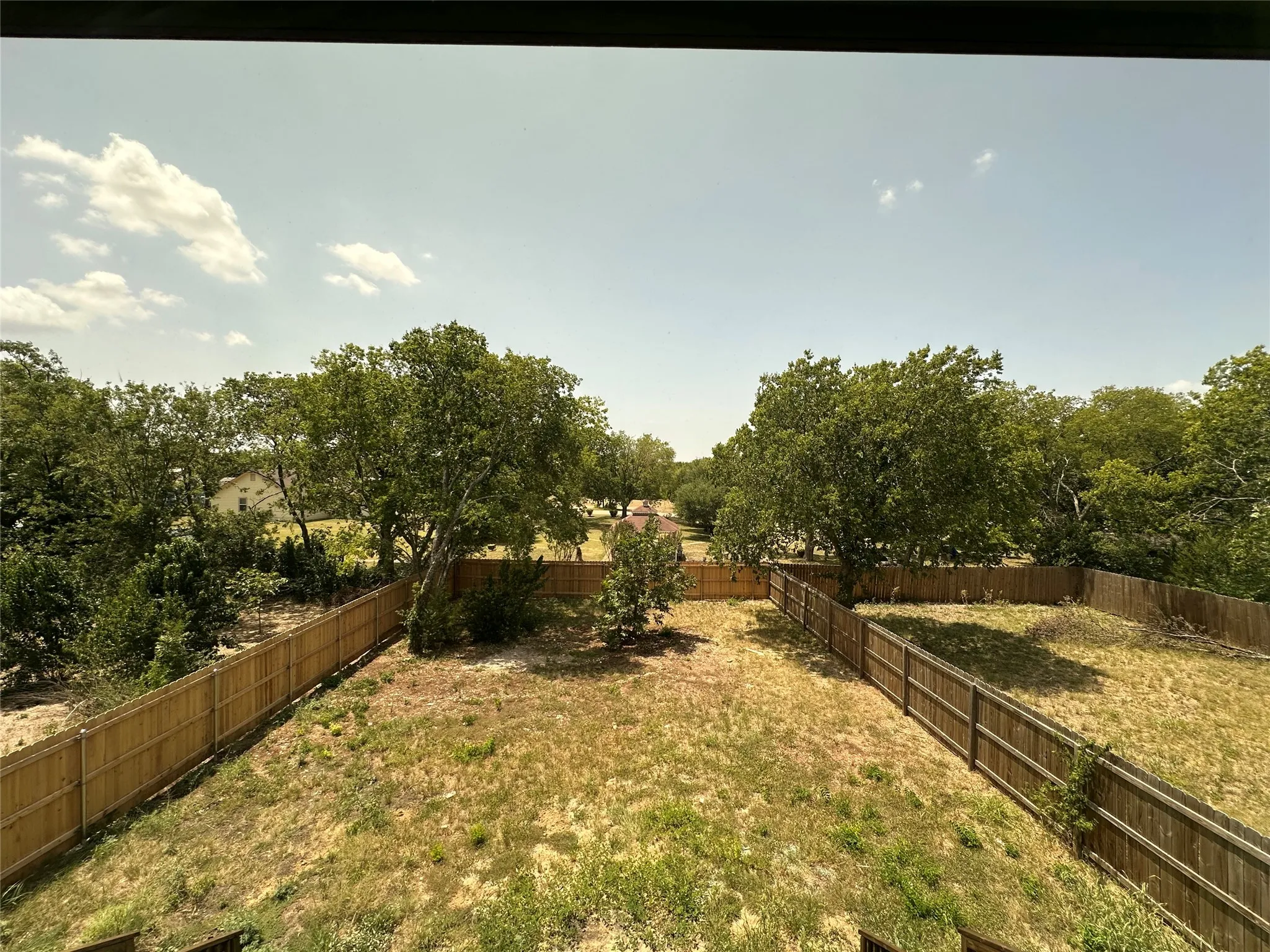Expansive outdoor area featuring mature trees and a perimeter fence