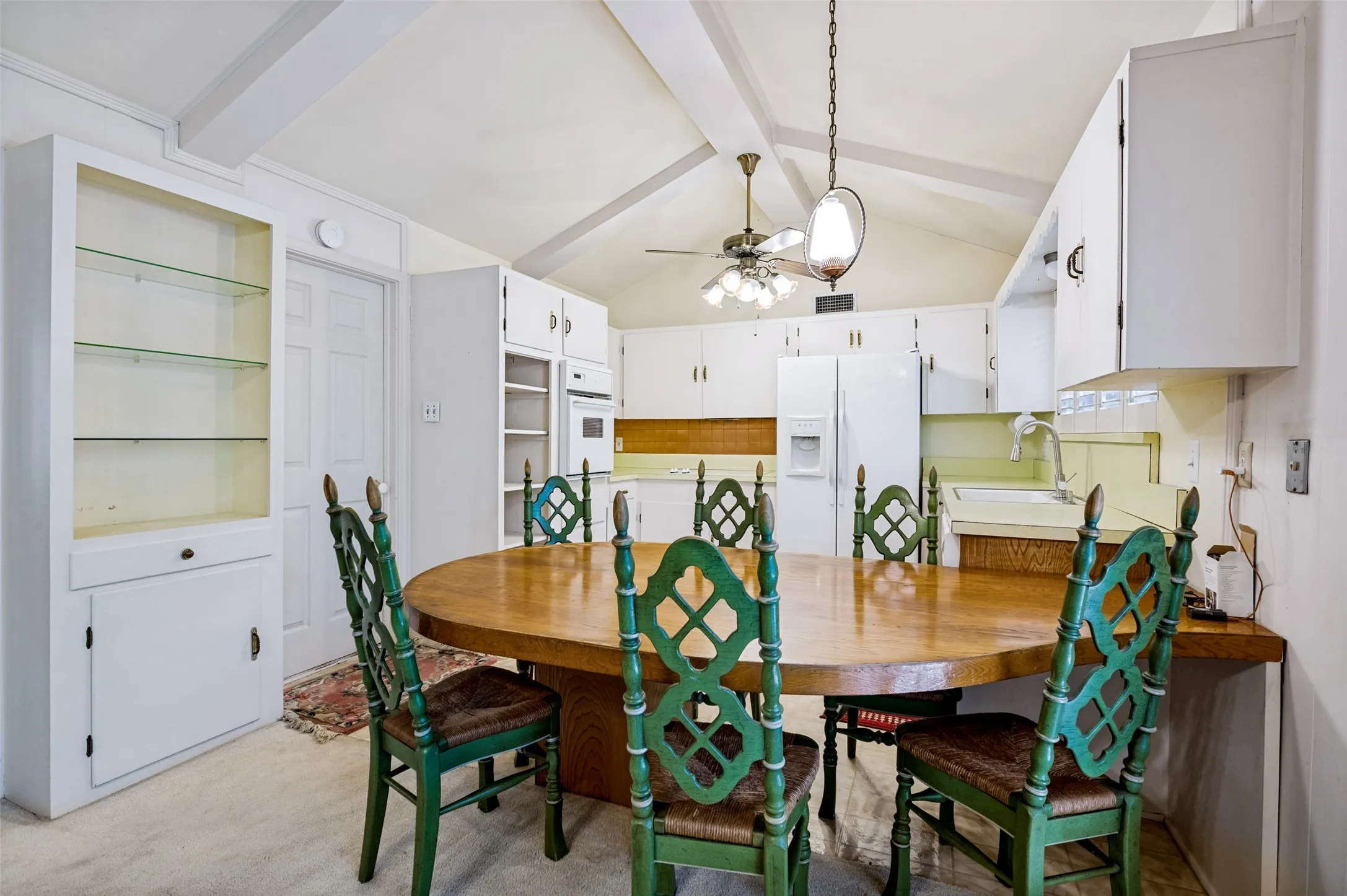 Vaulted ceiling with exposed beams, recessed lighting, built-in display cabinetry with glass shelving, integrated white appliances, and a tiled backsplash