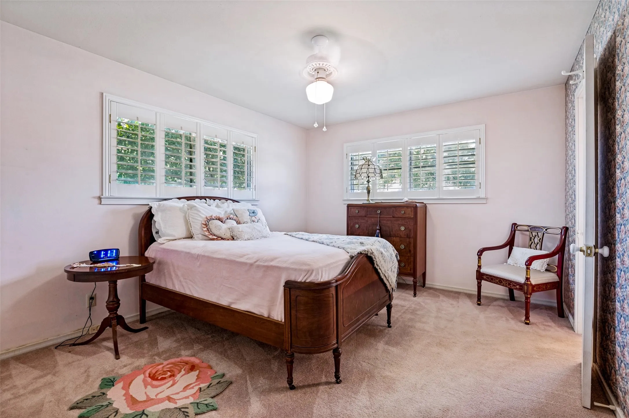 Recessed windows with plantation shutters, ceiling fan with integrated lighting, and neutral carpet flooring