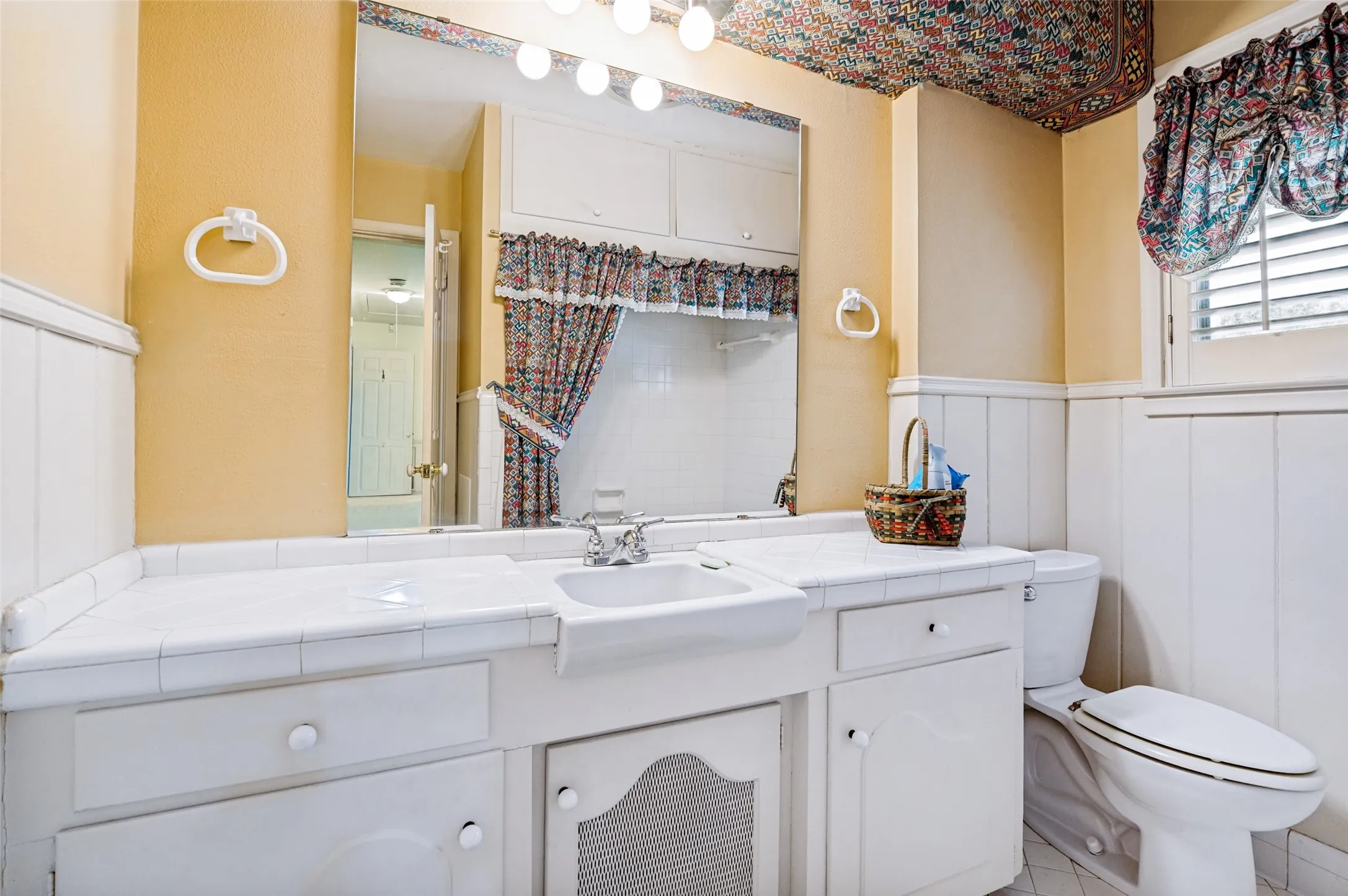 Vanity with an integrated sink, built-in cabinetry, wall-mounted mirror, and a toilet