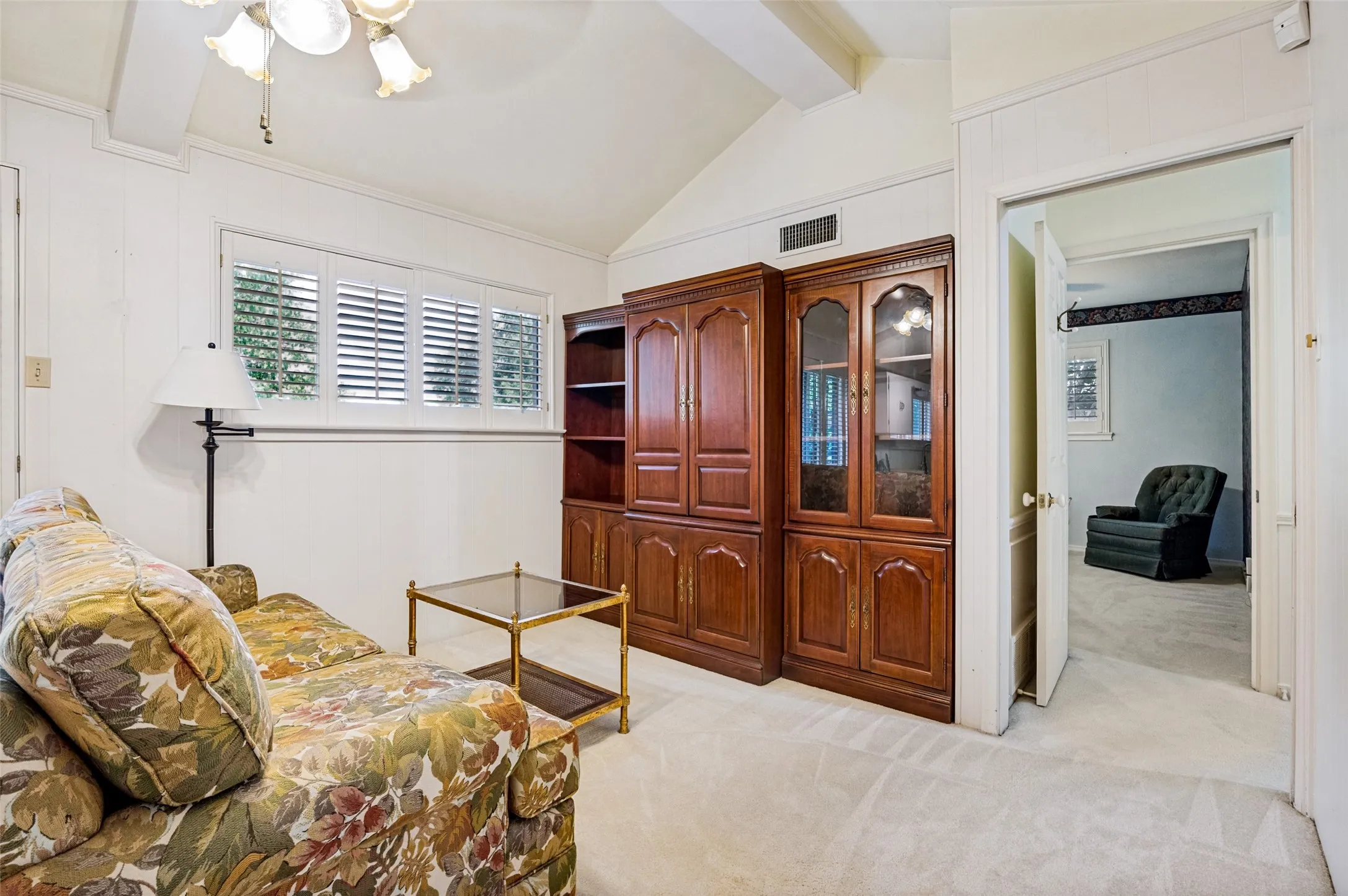 Vaulted ceiling with exposed beam, plantation shutters, built-in cabinetry, and wall-to-wall carpeting