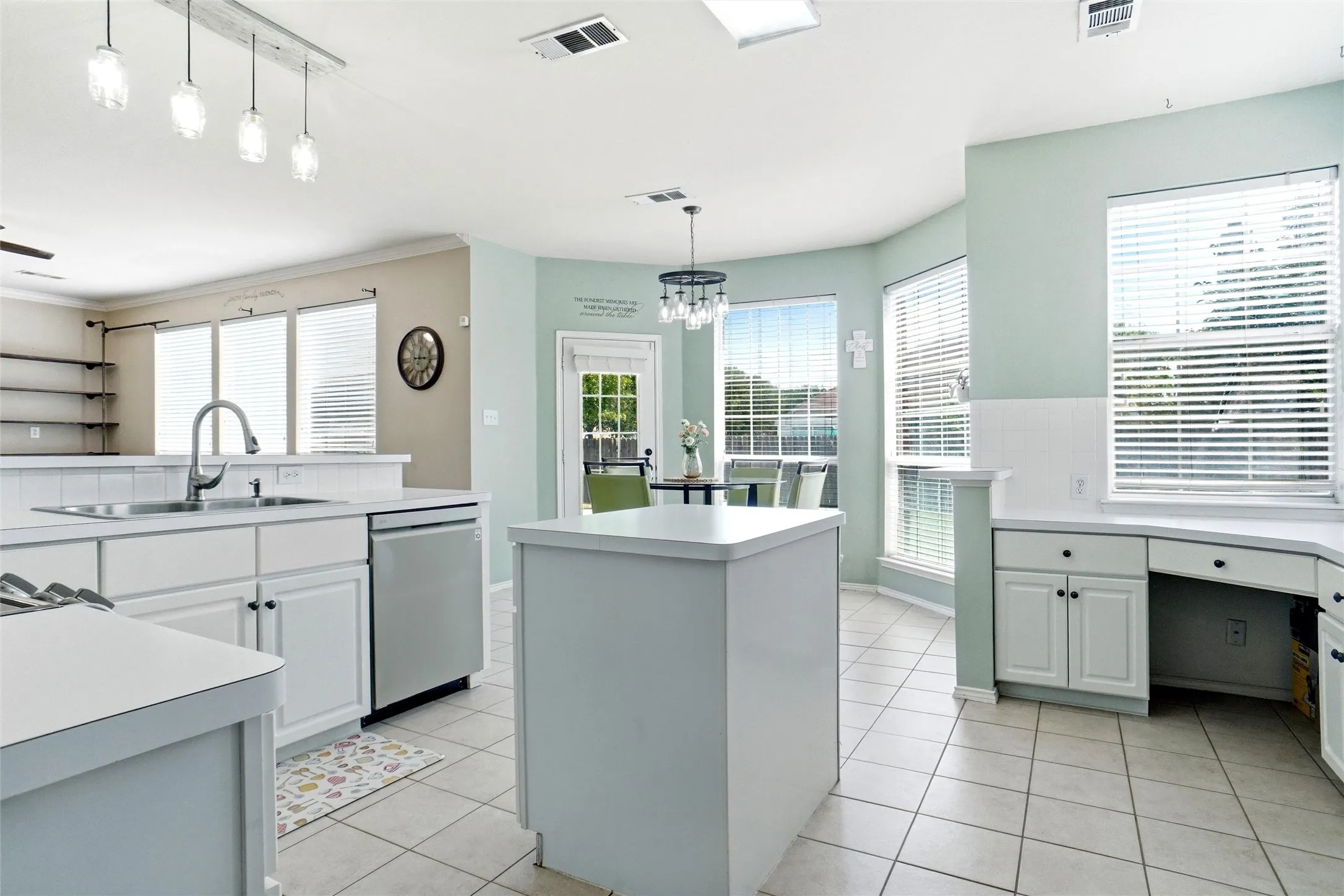 Bright kitchen and breakfast area featuring a center island, abundant cabinetry and counter space, built-in desk, and large windows that fill the space with natural light.