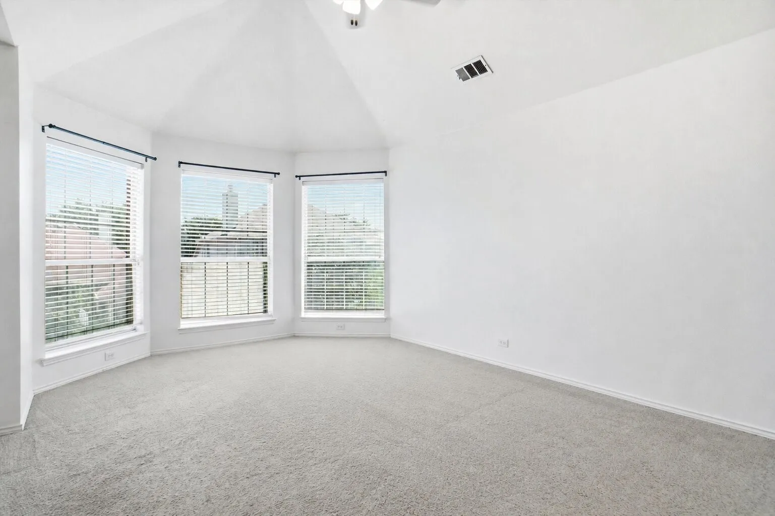 Spacious primary bedroom featuring vaulted ceilings, a wall of windows, and abundant natural light.