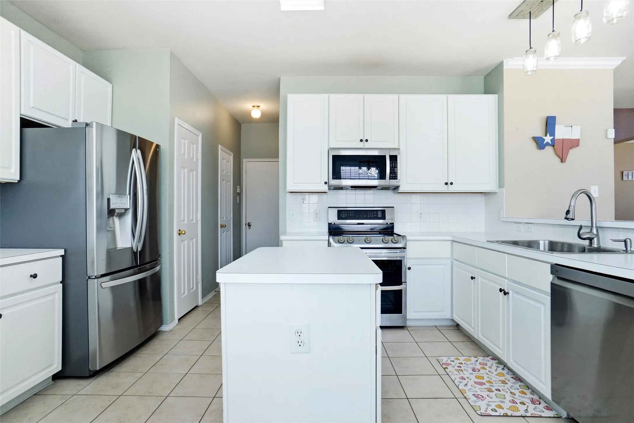 Bright kitchen featuring white cabinetry, stainless steel appliances, a center island, and plenty of cabinet and counter space.