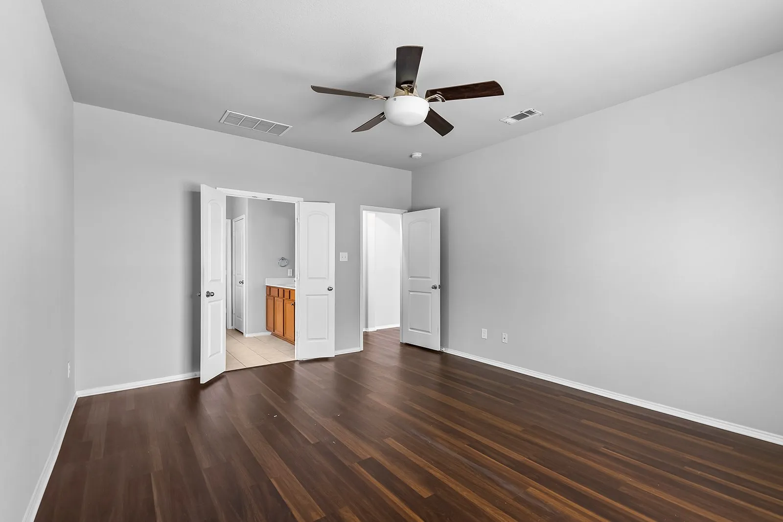 Spacious room with dark wood-finish flooring and light gray walls