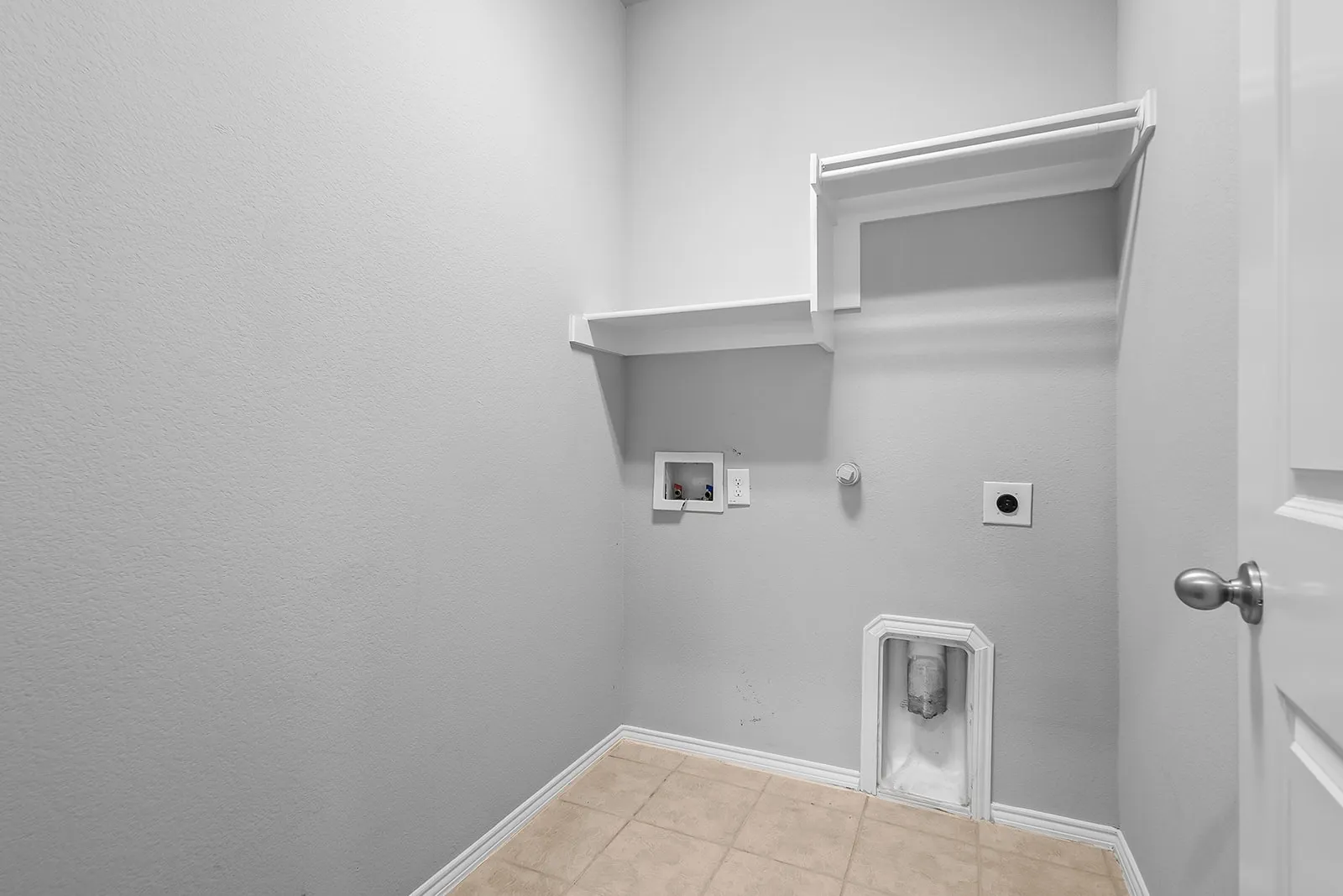 Utility room featuring ceramic tile flooring, built-in shelving, and a hanging rod
