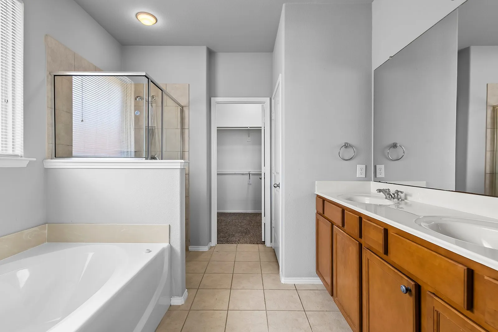 Bathroom featuring dual vanity with wood-finish cabinetry, white countertop, and integrated sinks