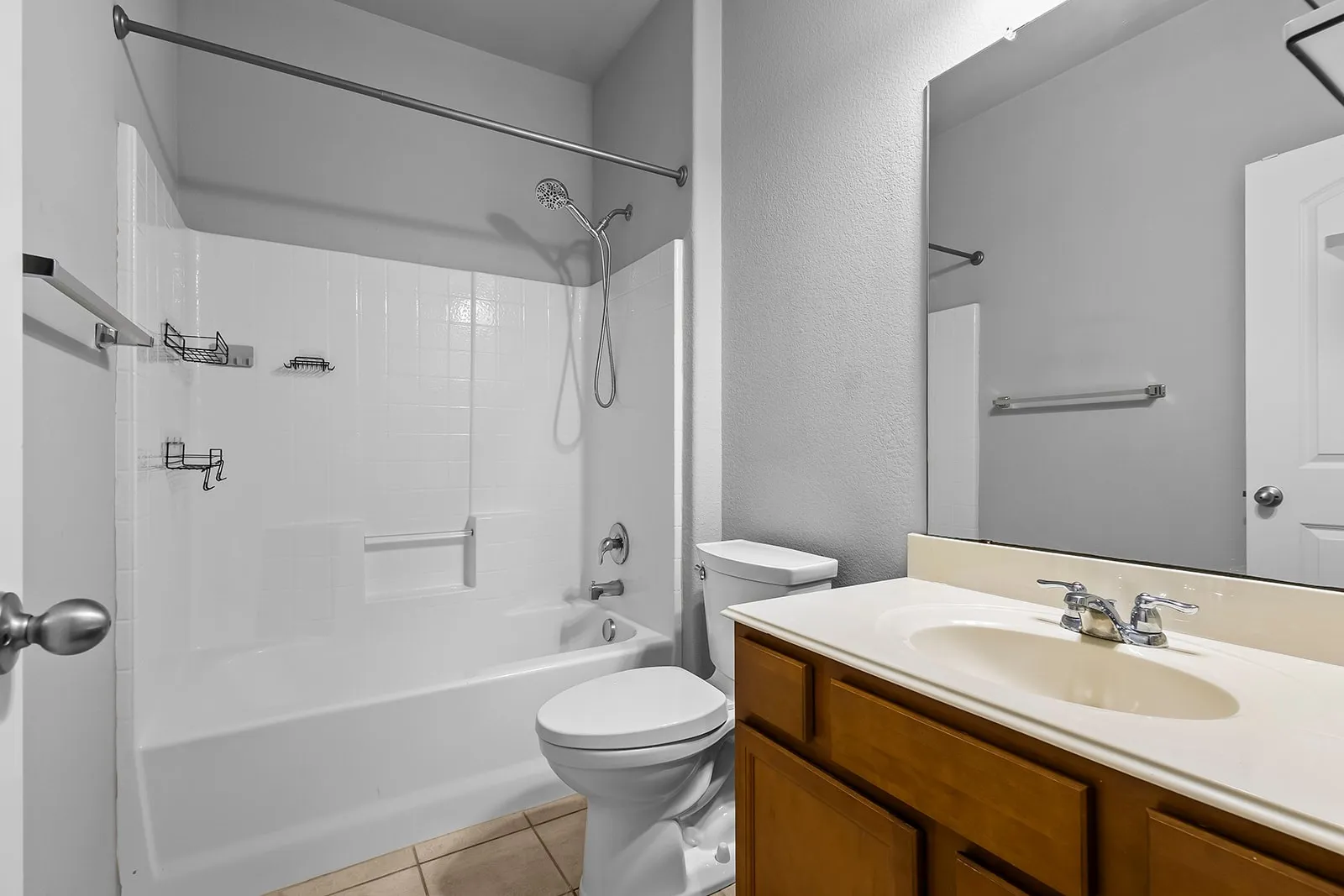 Full bathroom featuring a tub/shower combination with a textured surround, a single-sink vanity with a wood-finish cabinet, and a large wall-mounted mirror