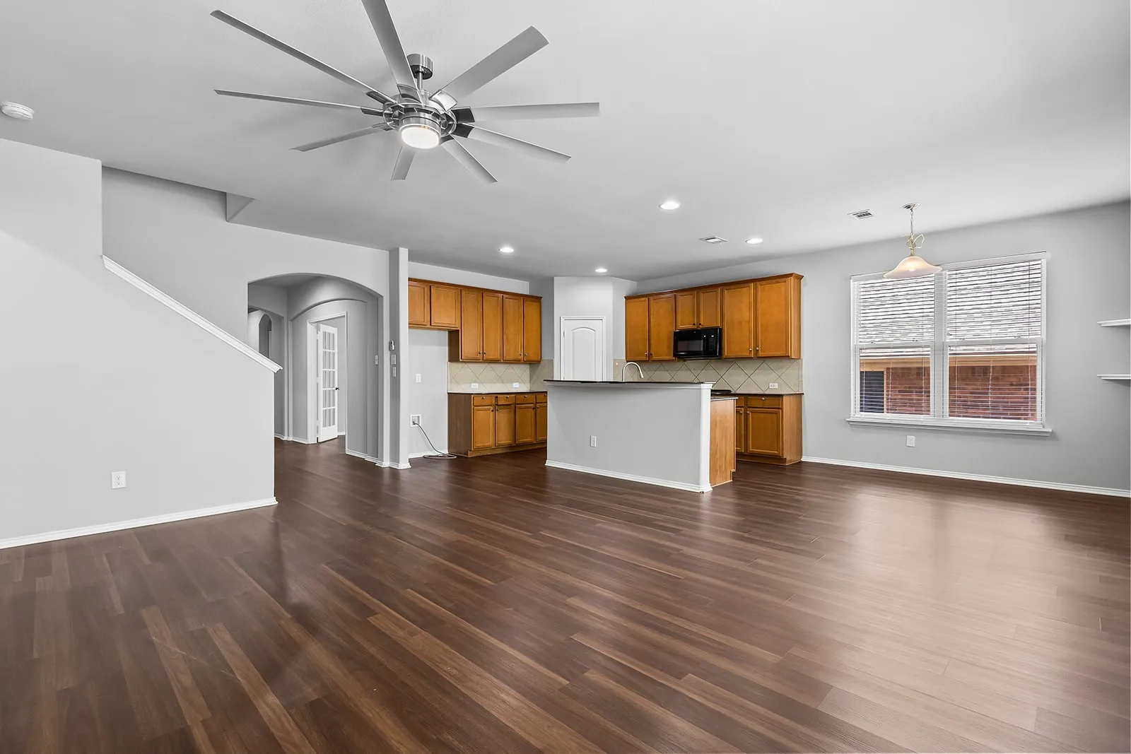 Open-concept living space featuring wood-finish flooring, a contemporary ceiling fan, and recessed lighting