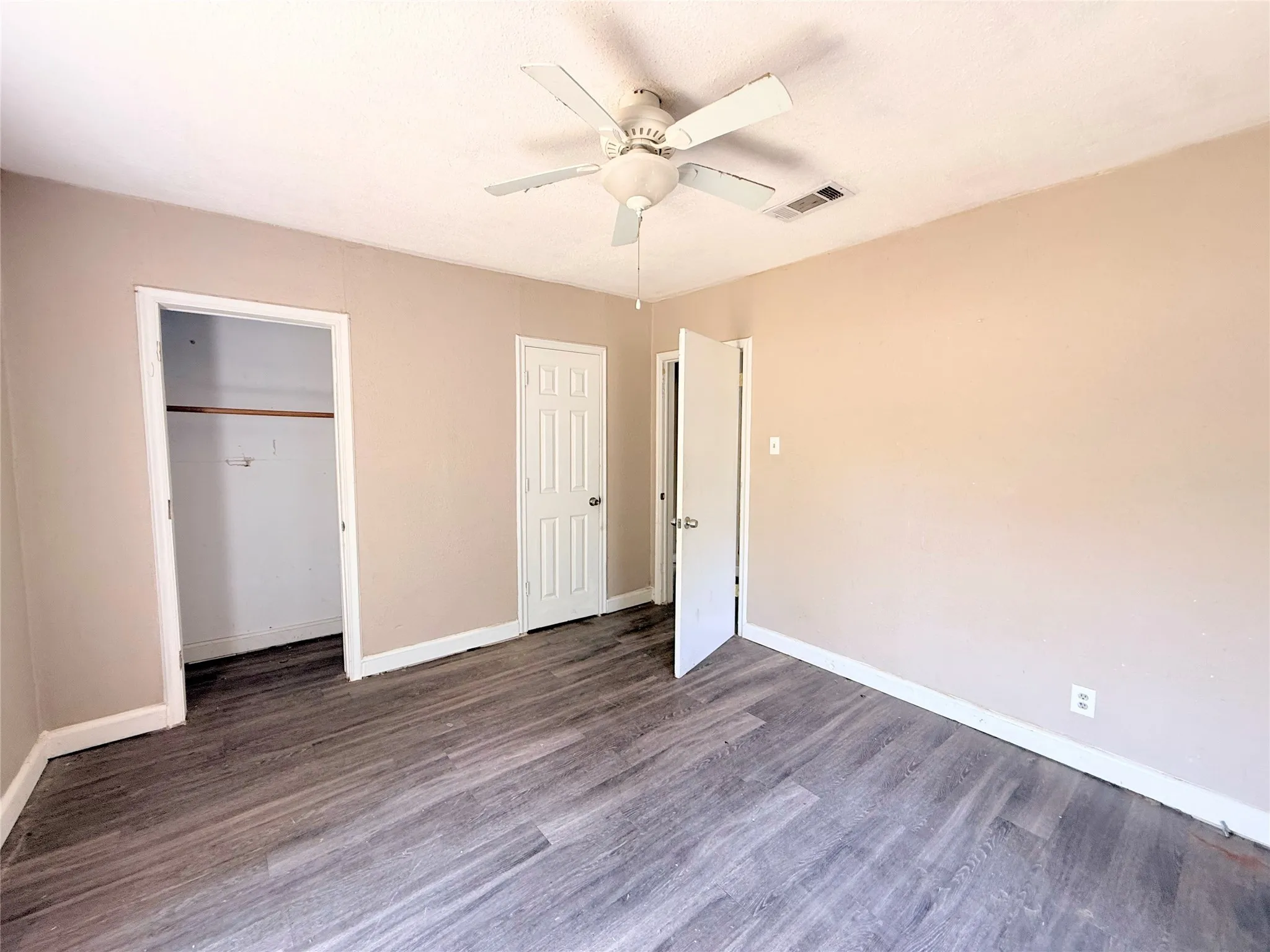 Room featuring wood-finish flooring, neutral wall tones, and a ceiling fan