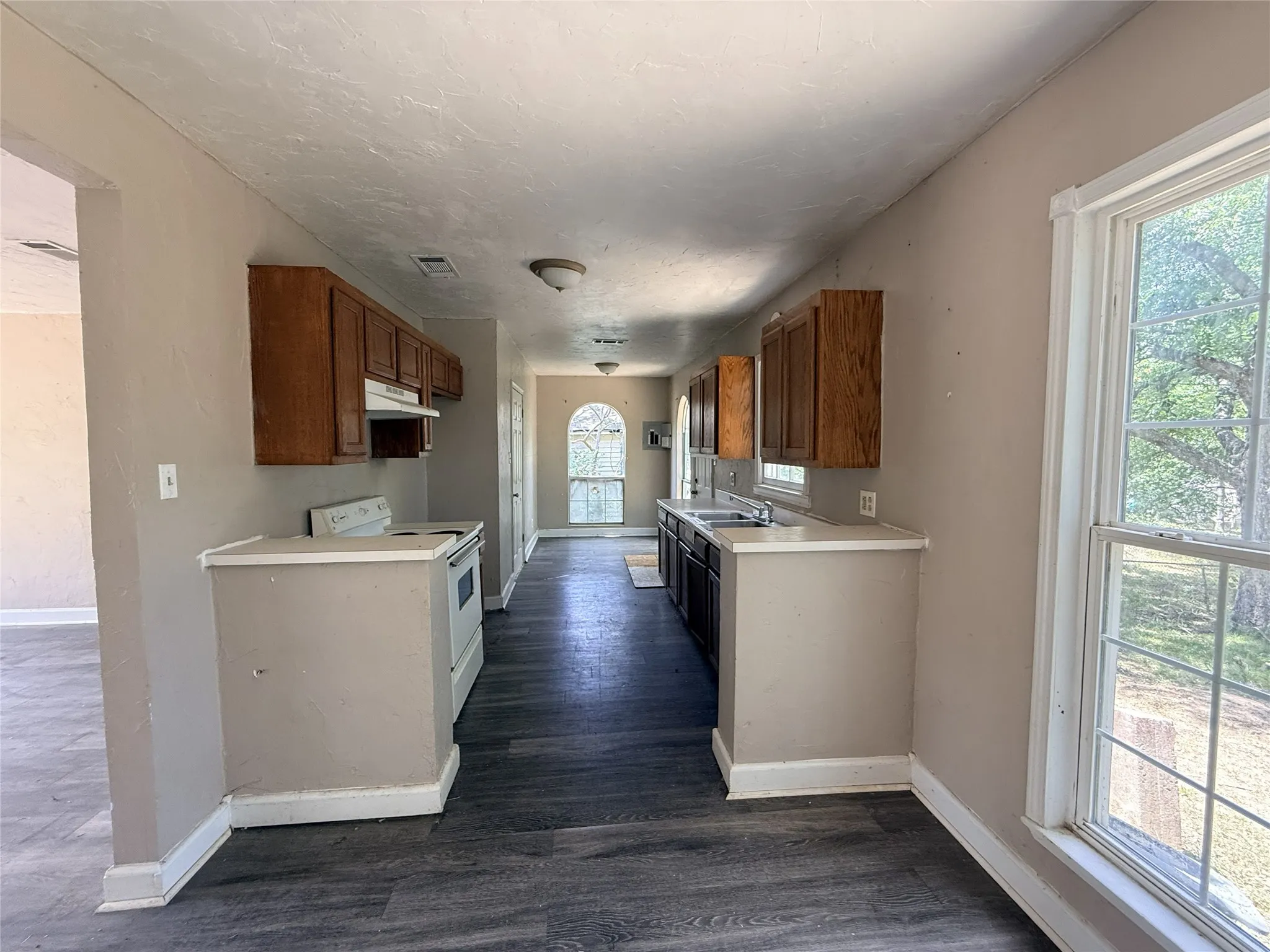 Galley kitchen featuring wood-finish cabinetry, a white electric range, and laminate countertops