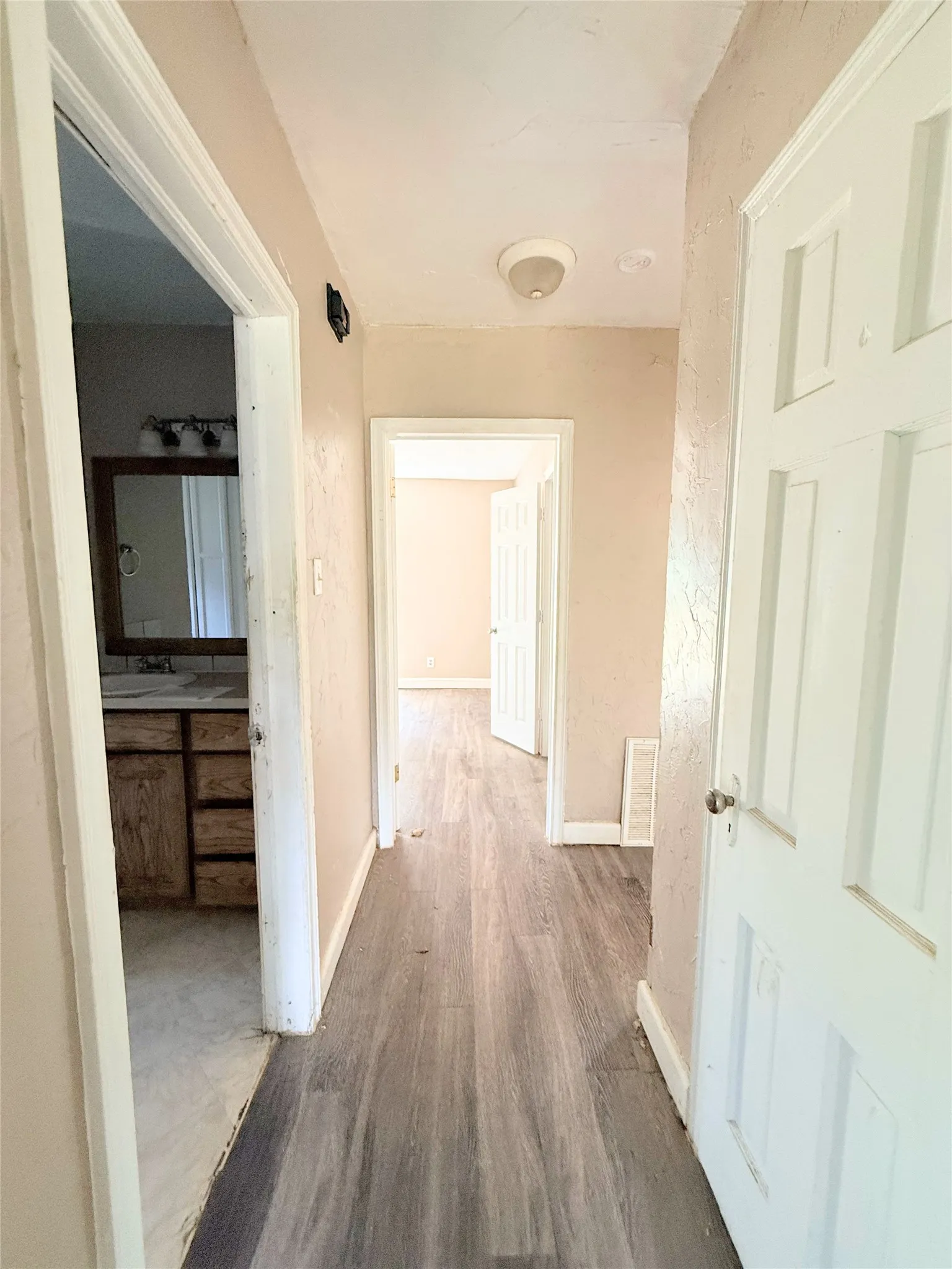 Hallway featuring wood-finish flooring, light-colored walls, and a ceiling-mounted light fixture