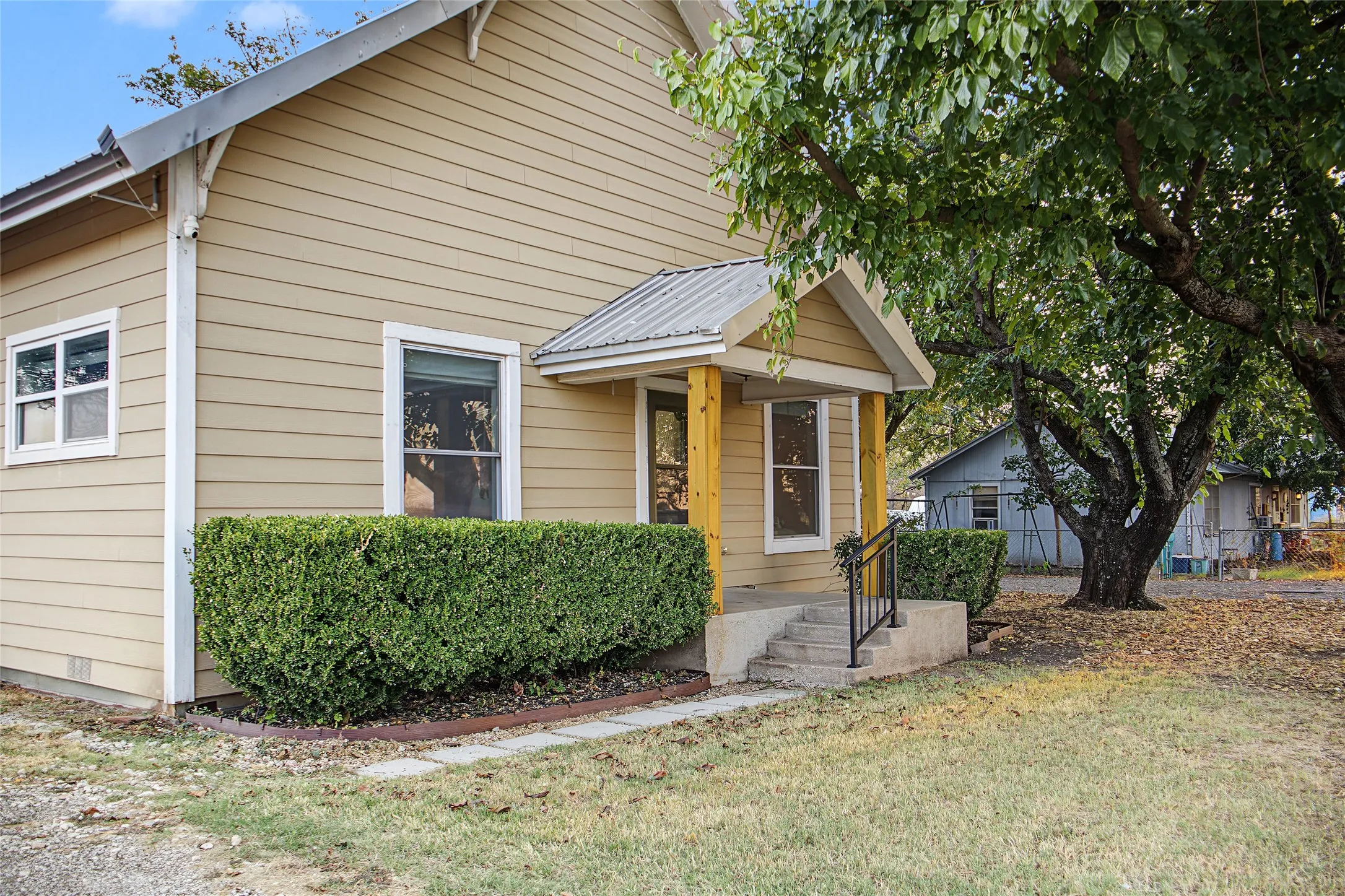 Siding exterior with decorative gable brackets, covered entry with wood support posts, and metal roof accent