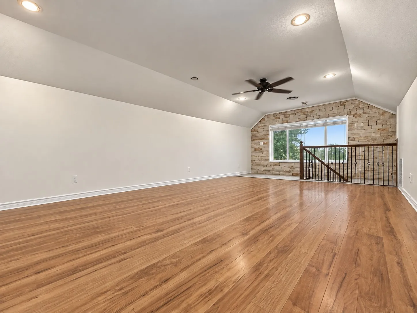 Spacious room featuring wood-finish flooring, recessed lighting, and a ceiling fan