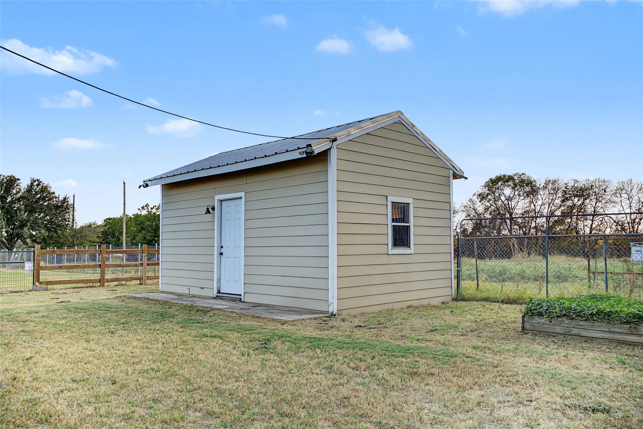 Detached storage building with siding exterior, metal roof, and a single window