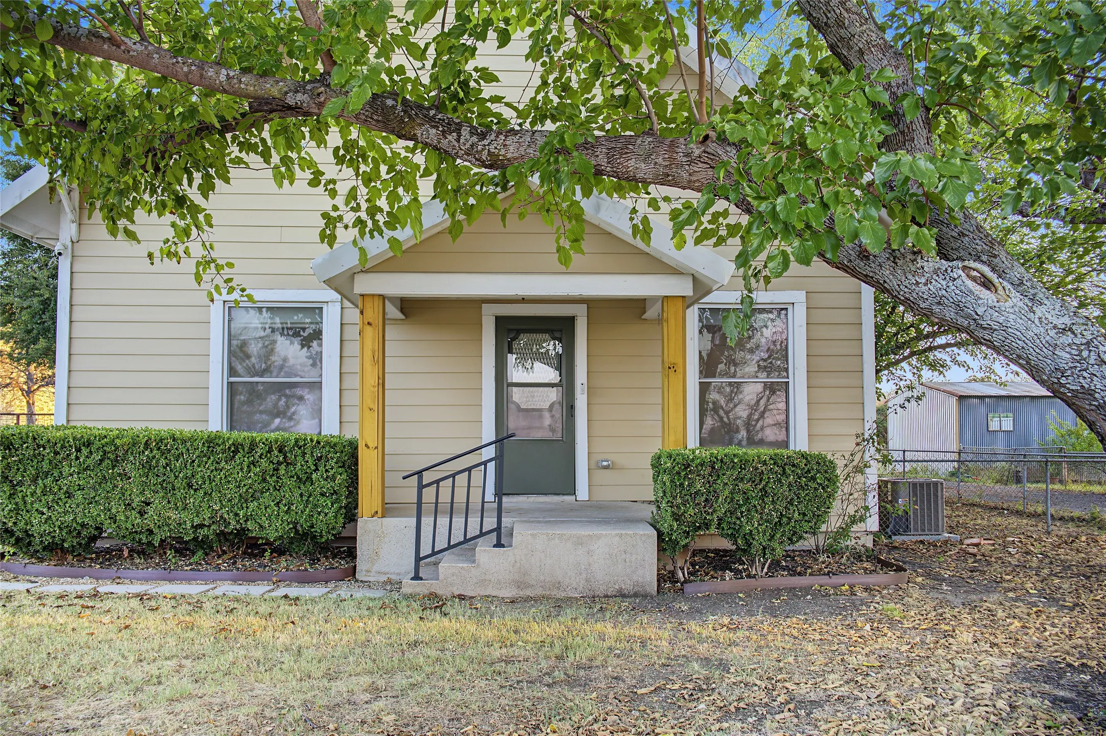 Siding exterior featuring a covered entry, concrete steps, and a black metal handrail