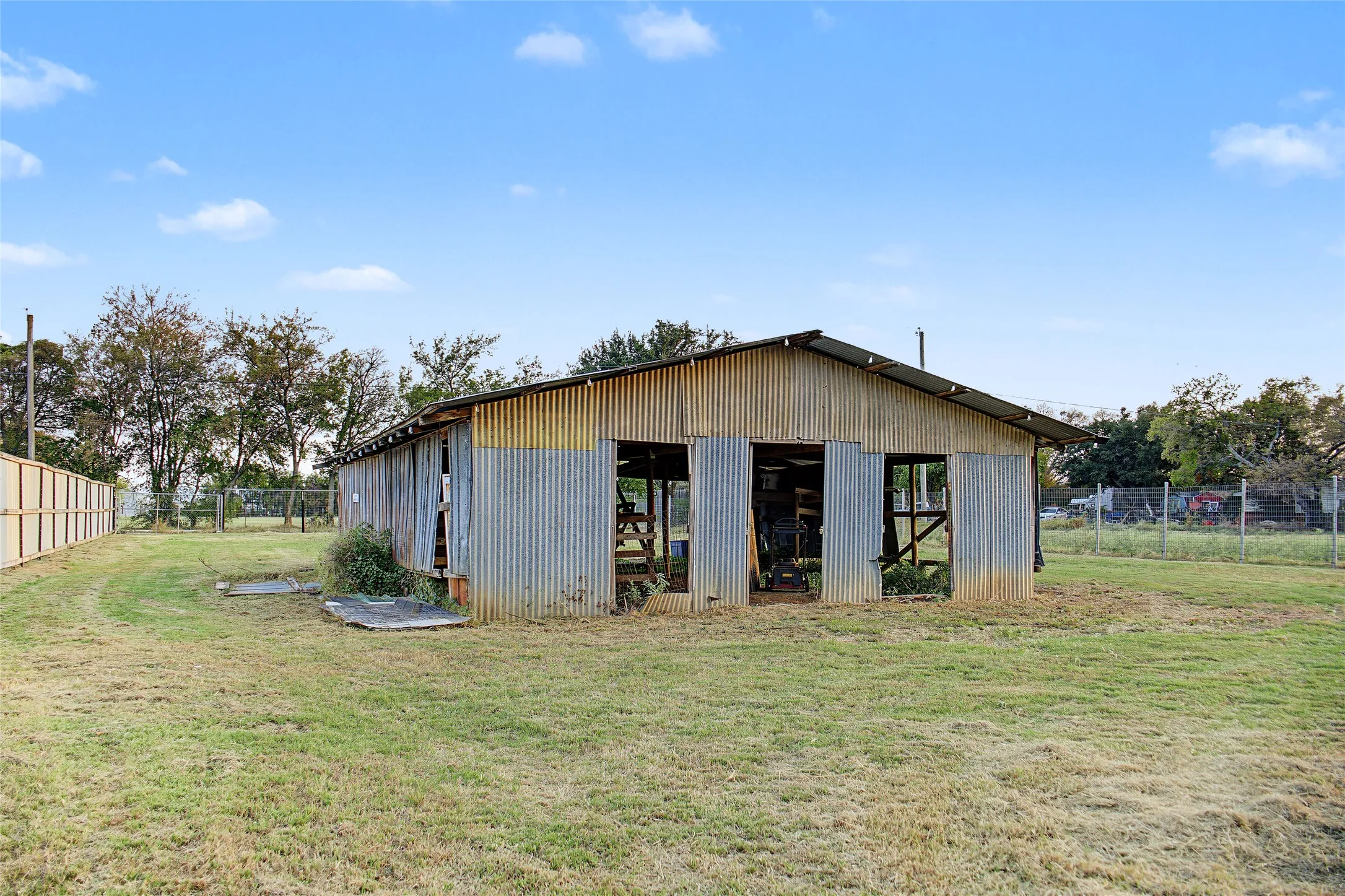 Corrugated metal structure with an open-sided design, pitched roof, and visible framing