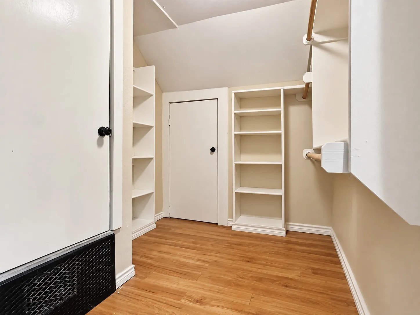 Wood-finish flooring, built-in shelving, white trim, and a white interior door