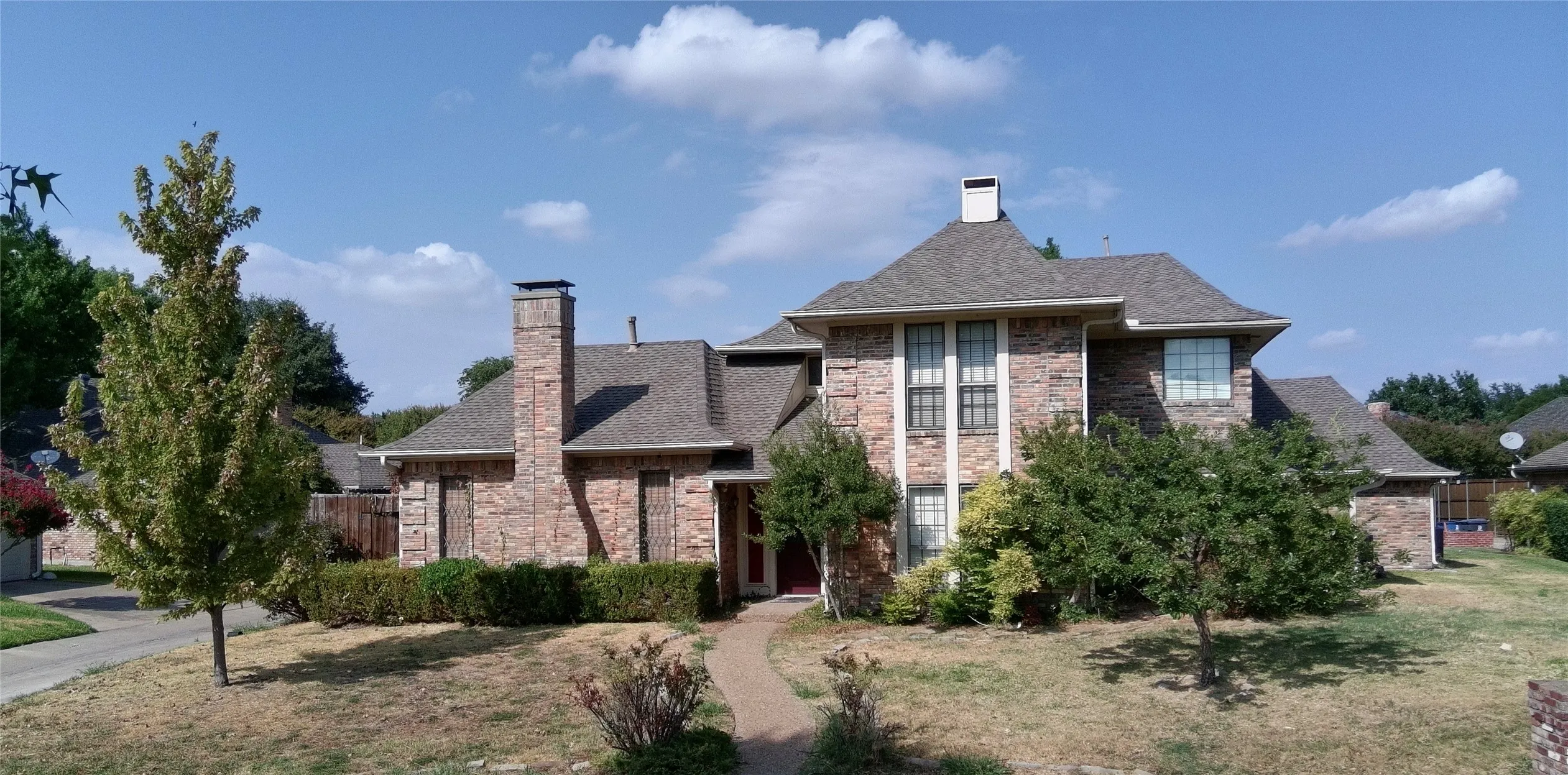 Front exterior with brick facade and mature landscaping
