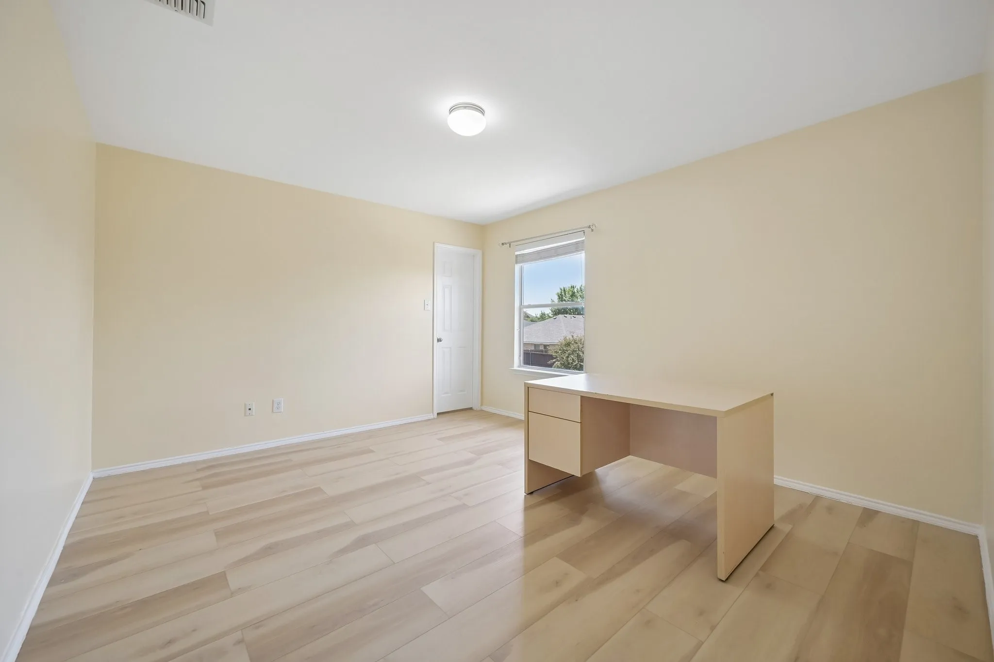 Wood-finish flooring throughout, light-colored wall paint, and a ceiling-mounted light fixture
