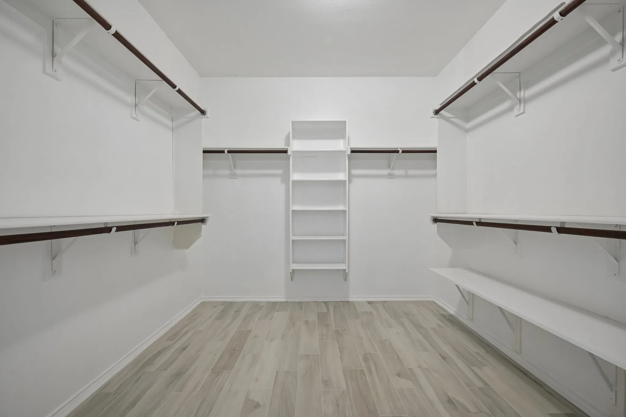 VIRTUALLY STAGED Bright and airy living space showcasing vaulted ceilings with ceiling fan, multiple windows with natural light, warm neutral wall finishes, wood-finish flooring, and a built-in planter accent
