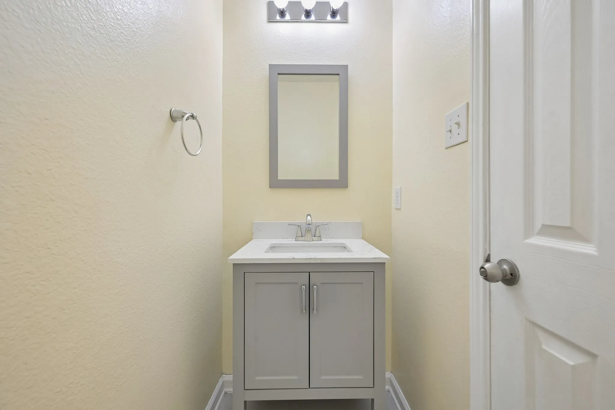 Vanity with gray shaker-style cabinetry, white countertop, and brushed nickel hardware