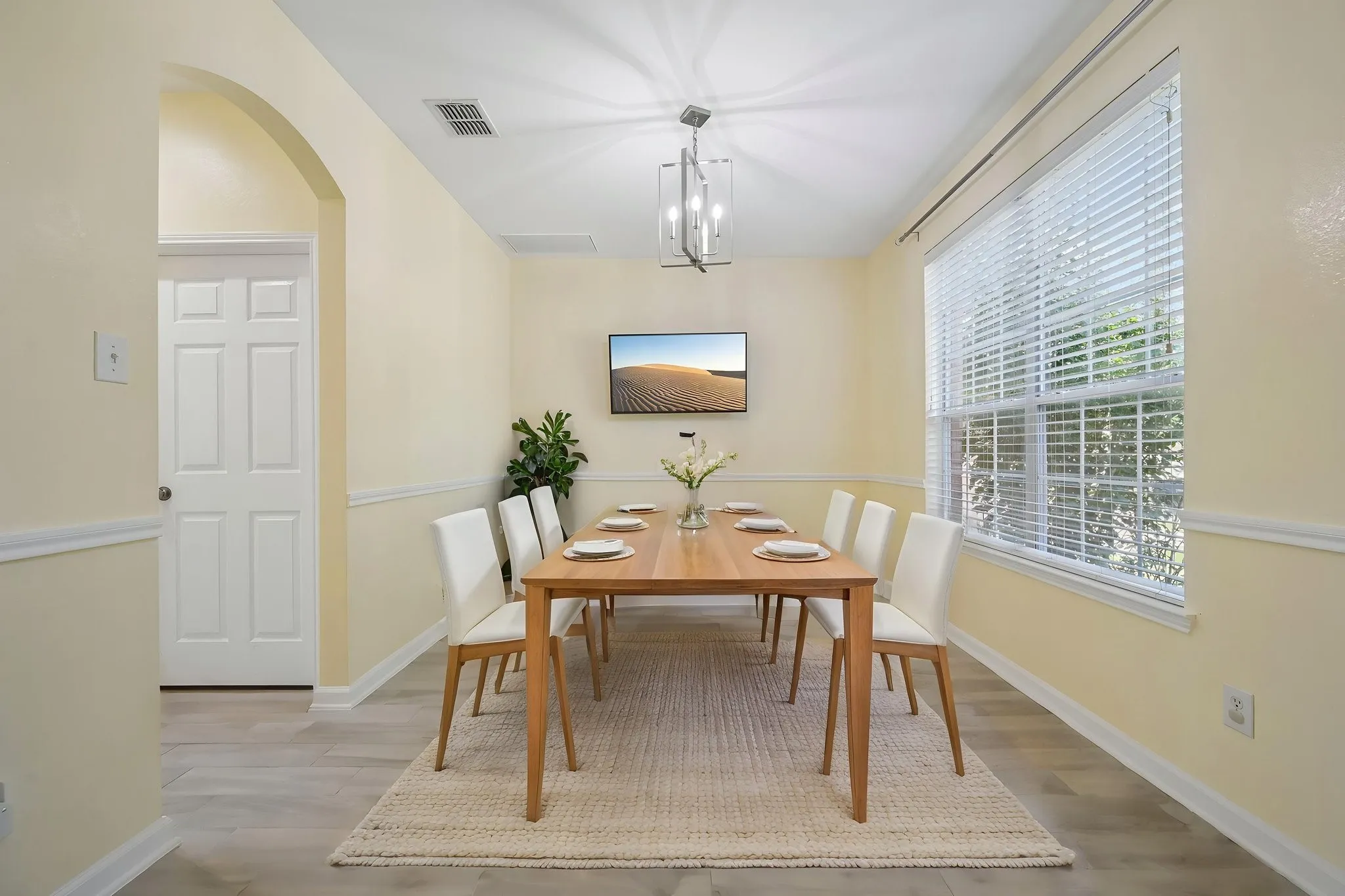VIRTUALLY STAGED Elegant dining room bathed in natural light from oversized windows with plantation shutters