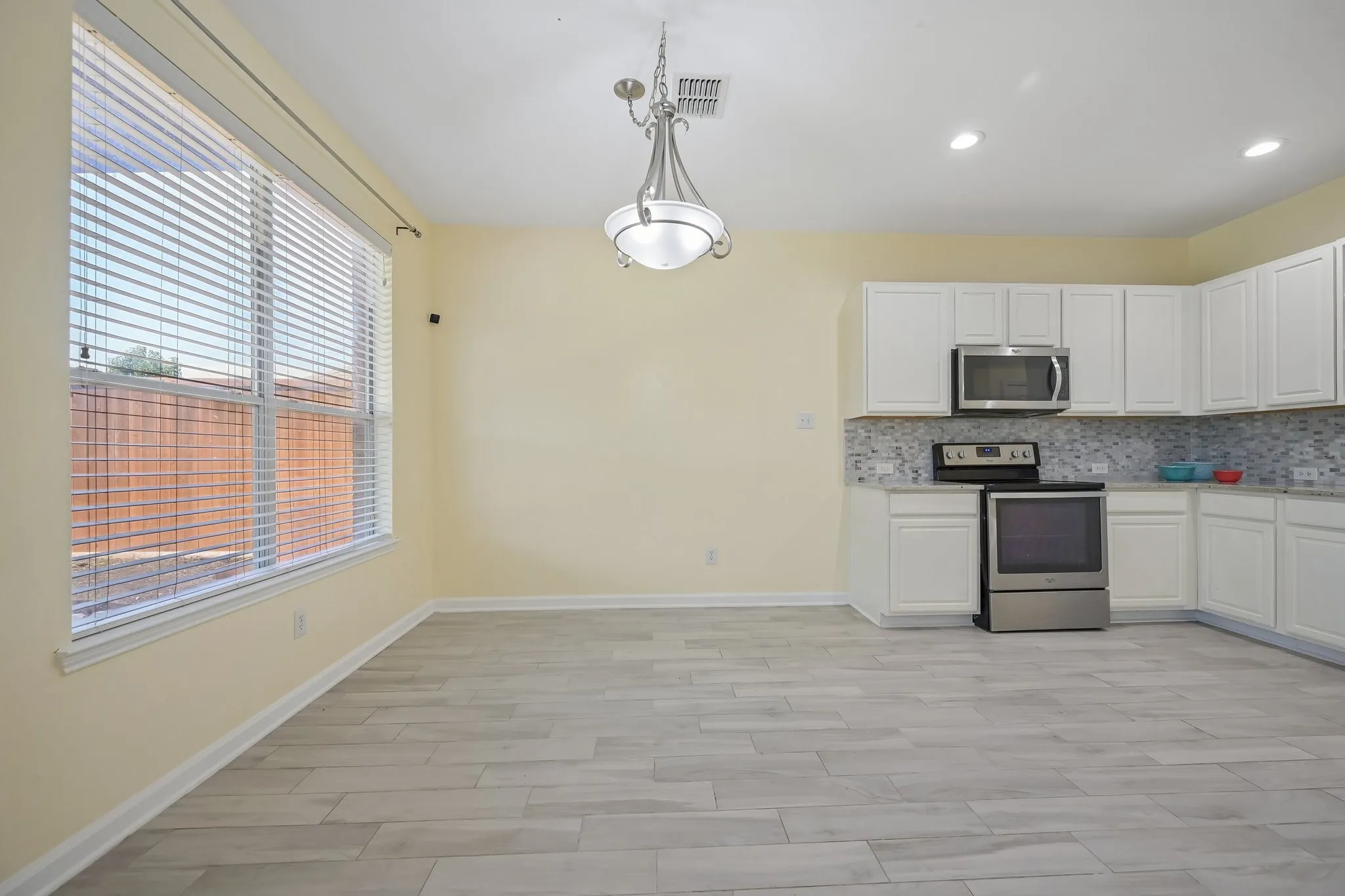 Kitchen with white cabinetry, stainless steel appliances, granite-style countertops, and a full tile backsplash