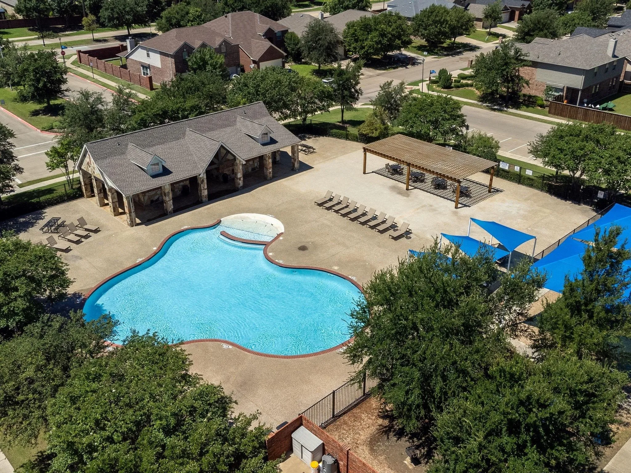 Resort-style pool with integrated spa, expansive pool deck, covered stone pavilion, and separate shaded pergola