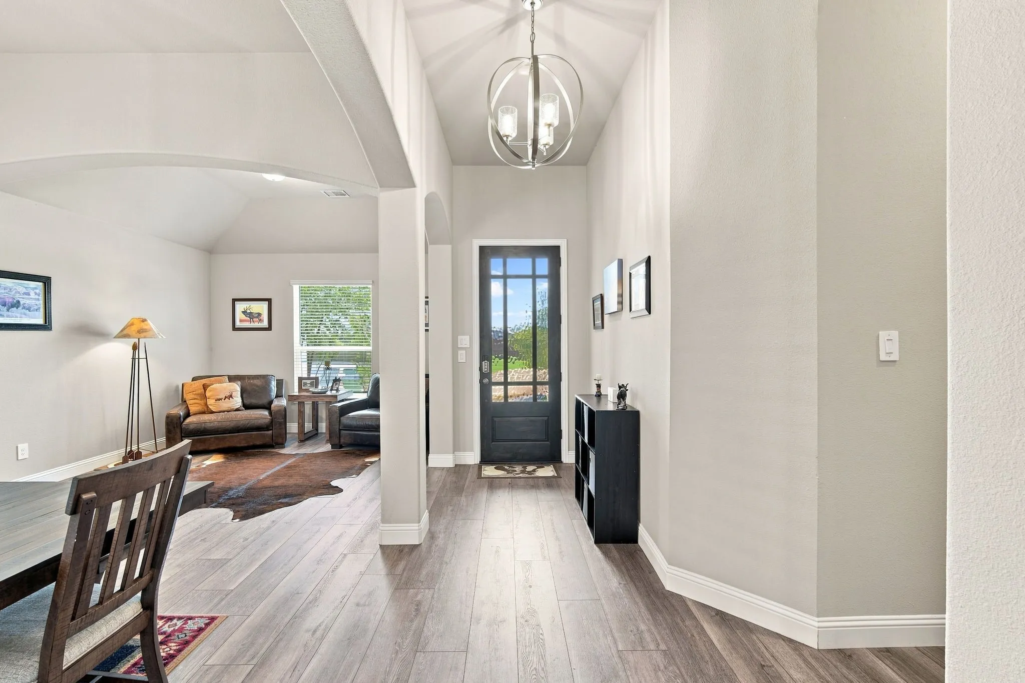 Arched entryway with a decorative chandelier, wood-finish flooring, and crisp white trim